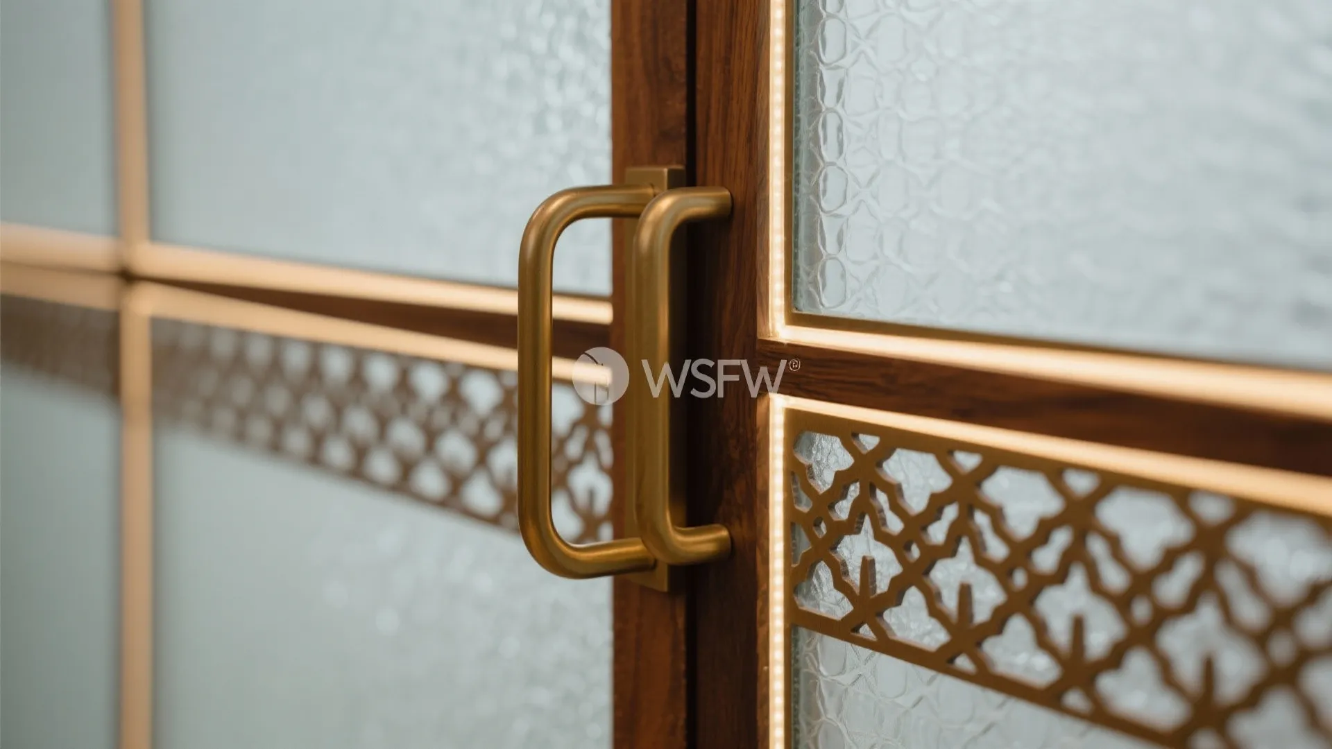 Close-up of frosted glass and teak jaali partition with satin brass handle and clean joinery.