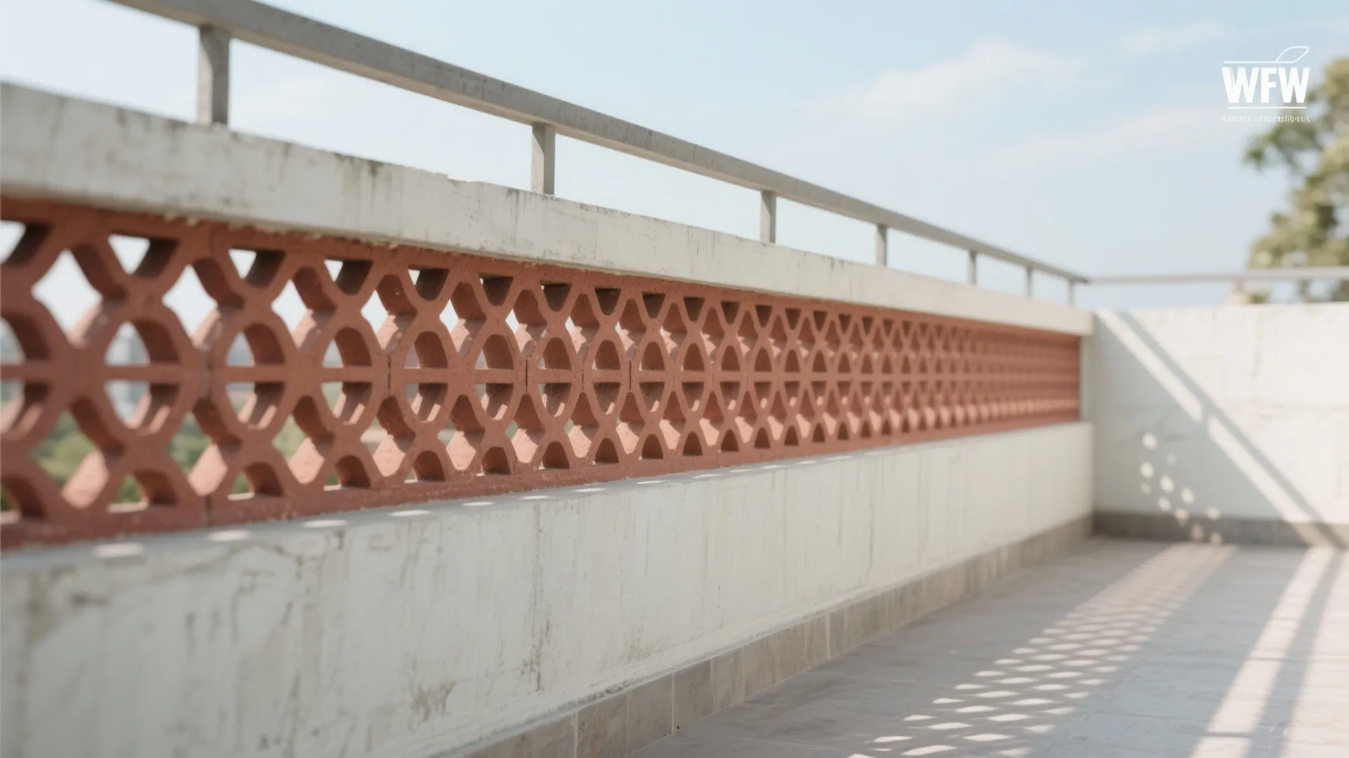 Rooftop balcony wall with a red patterned hollow brick screen and a simple metal safety railing