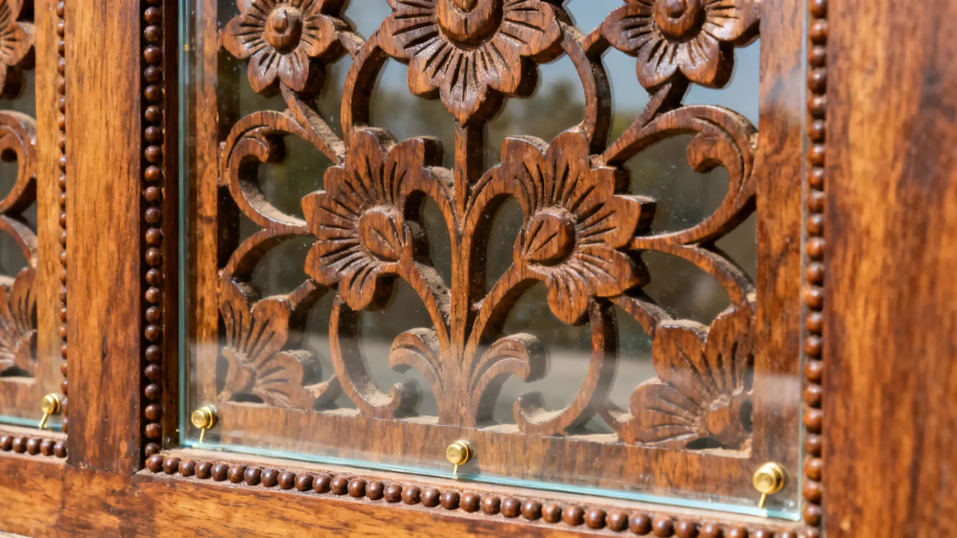 Detailed close view of a dark brown wood door with carved flower patterns and clear glass