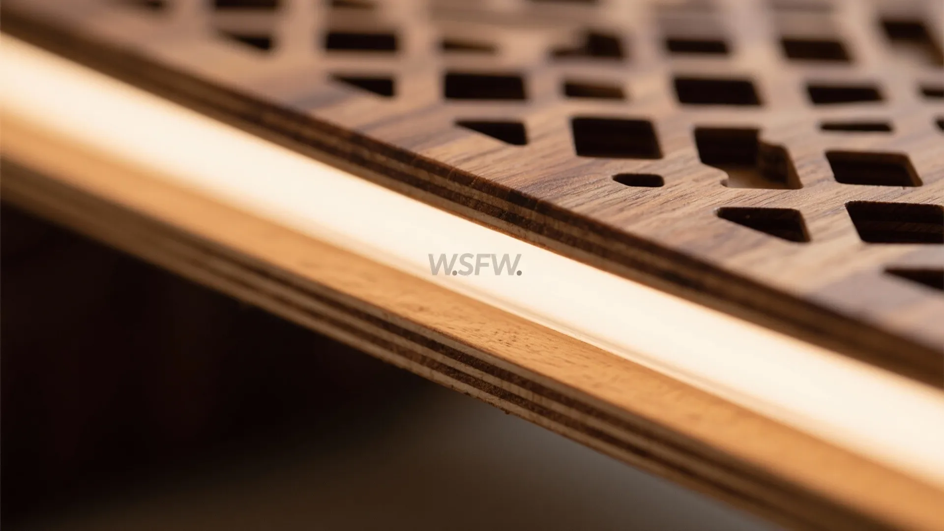 Close up view of warm LED light strip glowing underneath a decorative wooden wall panel