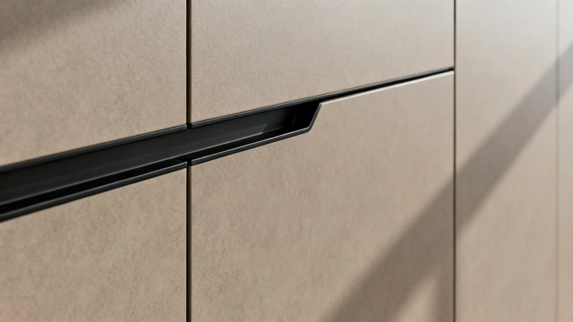 Macro of a matte taupe J-pull handleless cabinet groove with soft-close hardware detail.