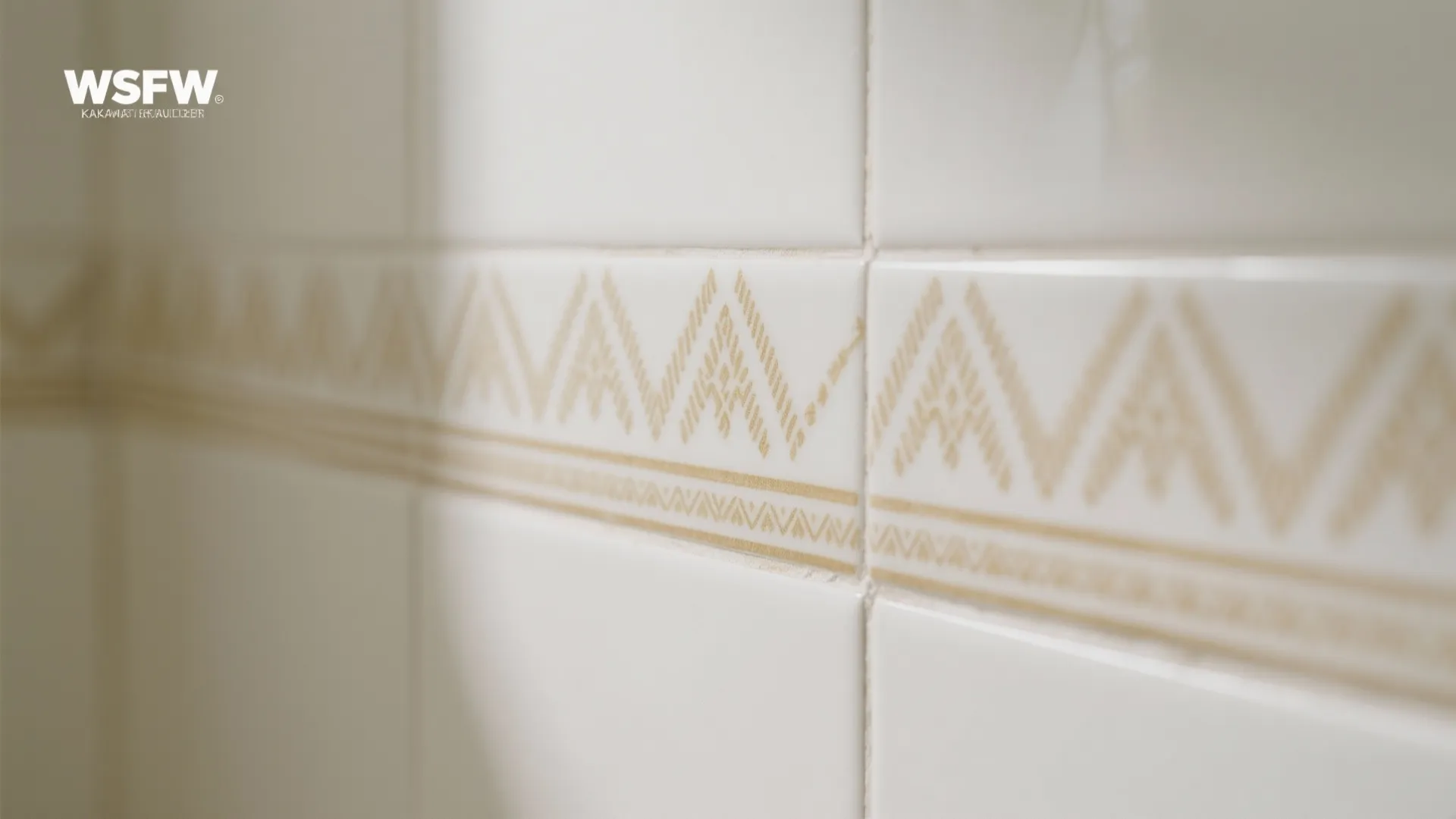 Macro of vitrified wall tiles with Kasavu-inspired gold-beige frieze on off-white satin finish.