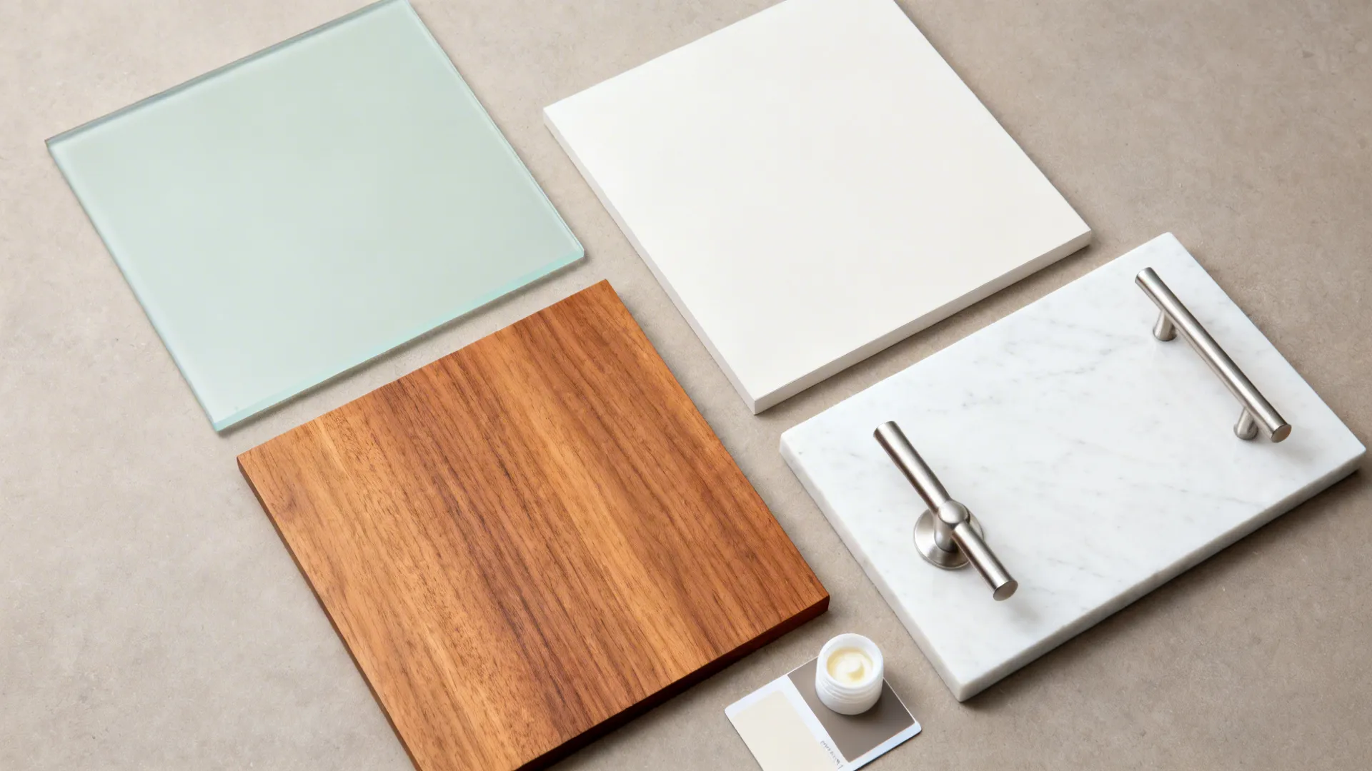 Top-down flat lay of sage glass, white laminate, teak veneer, quartz, and stainless hardware.
