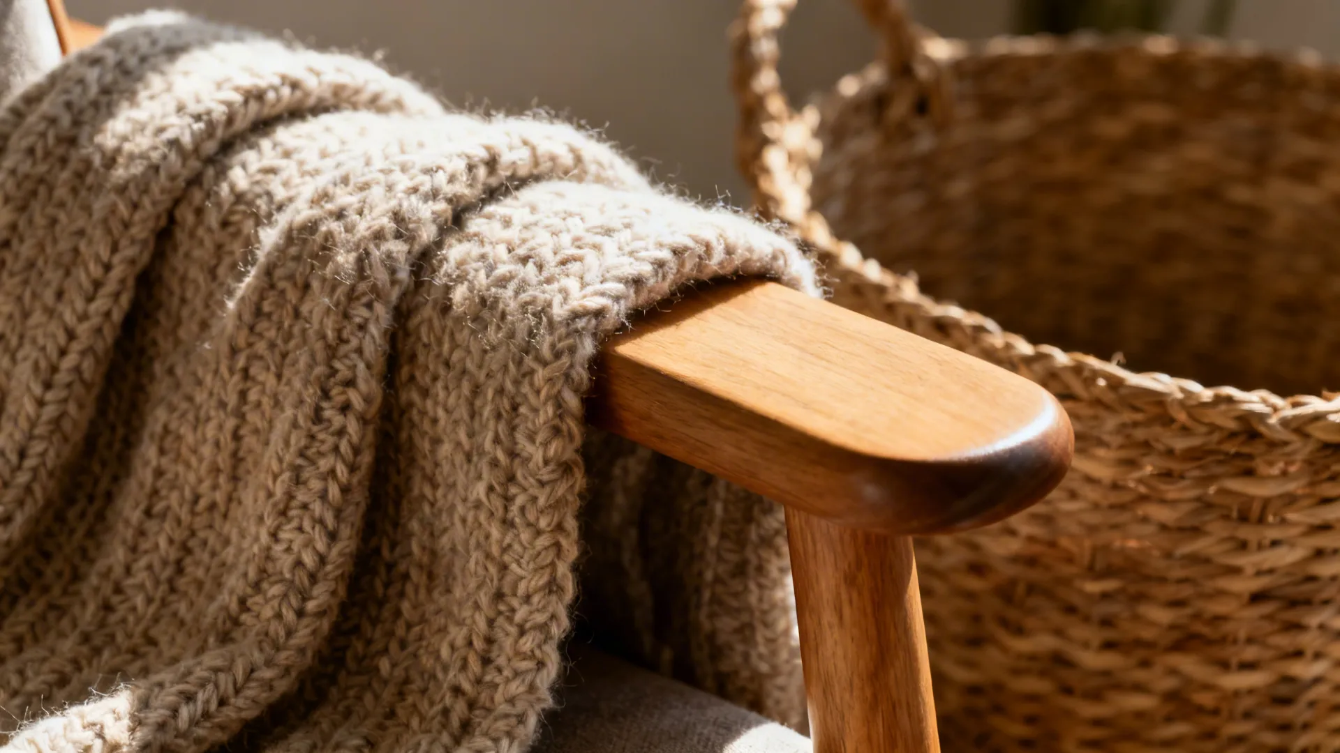 Macro of knit throw on a smooth wood chair beside a woven basket highlighting tactile contrast.