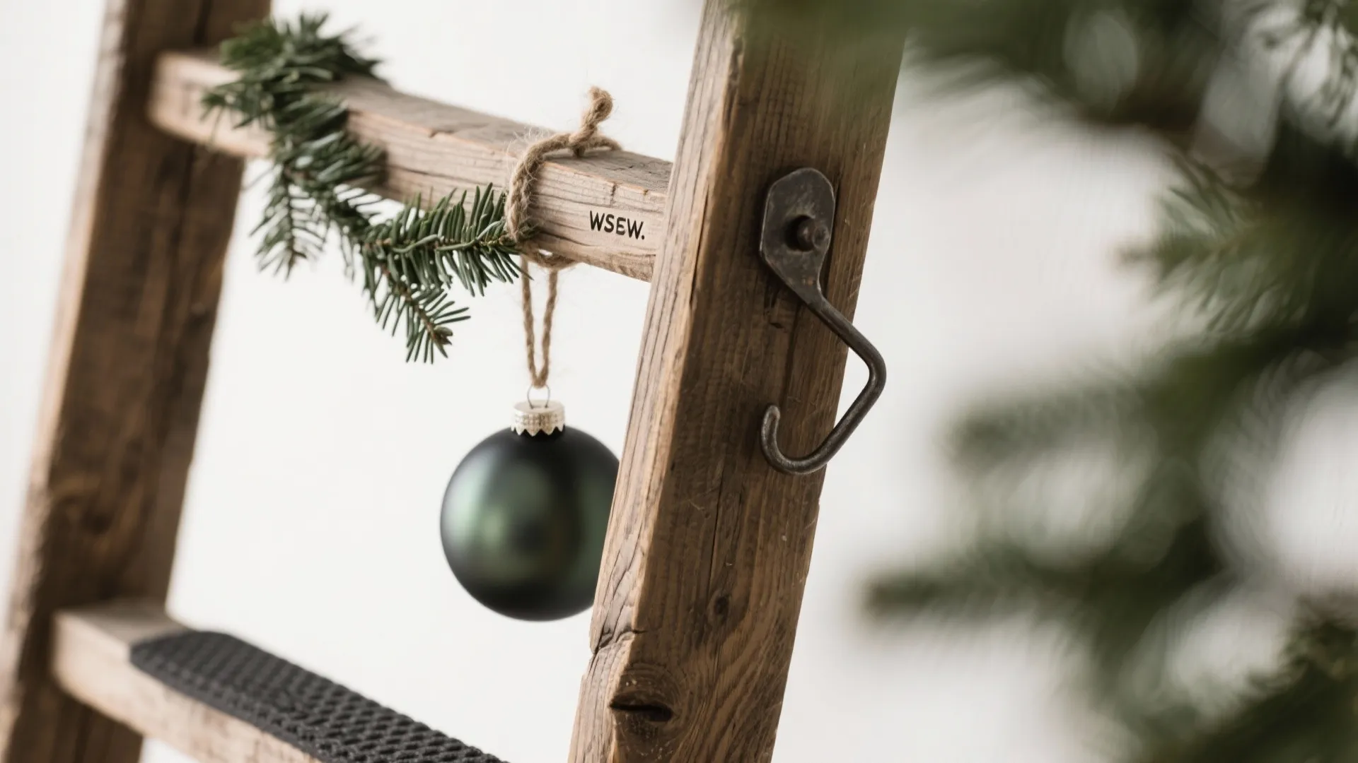 Close up of a wooden ladder decorated with green pine branches and a dark green ball