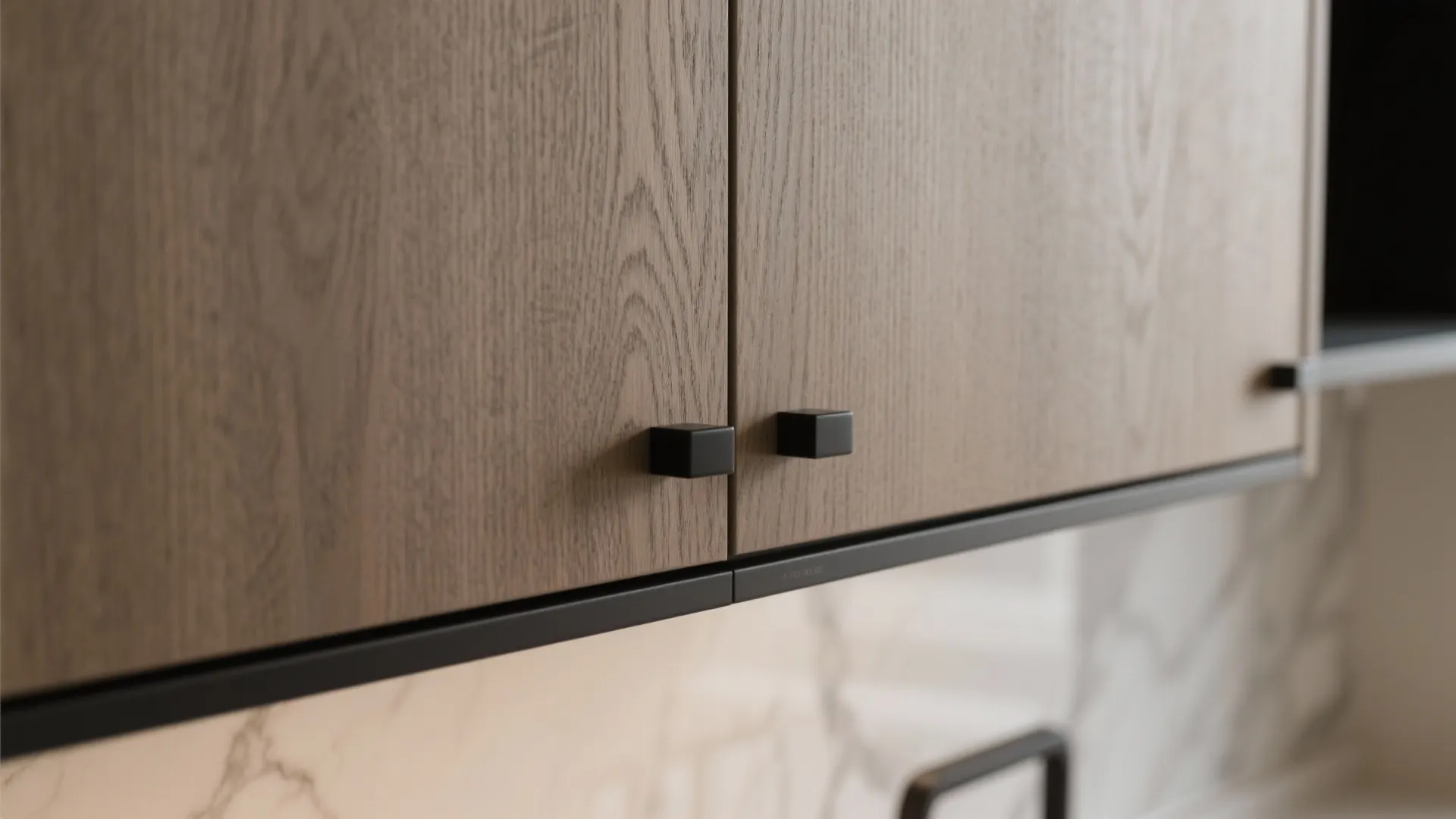 Close up view of wooden kitchen cabinet doors with small black square handles and frames