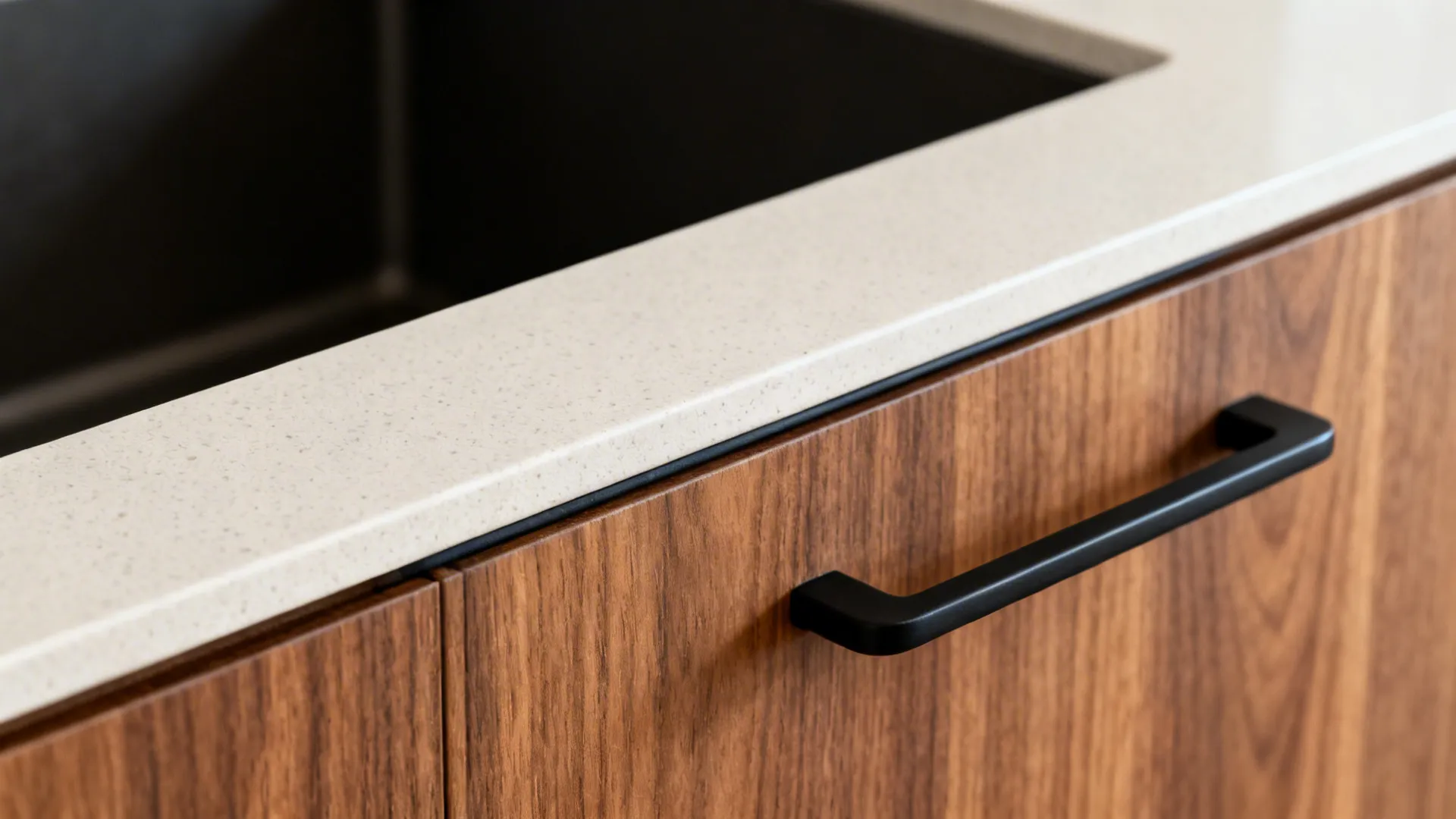 Macro of teak-look laminate, sealed edge, pale quartz, and matte black handle