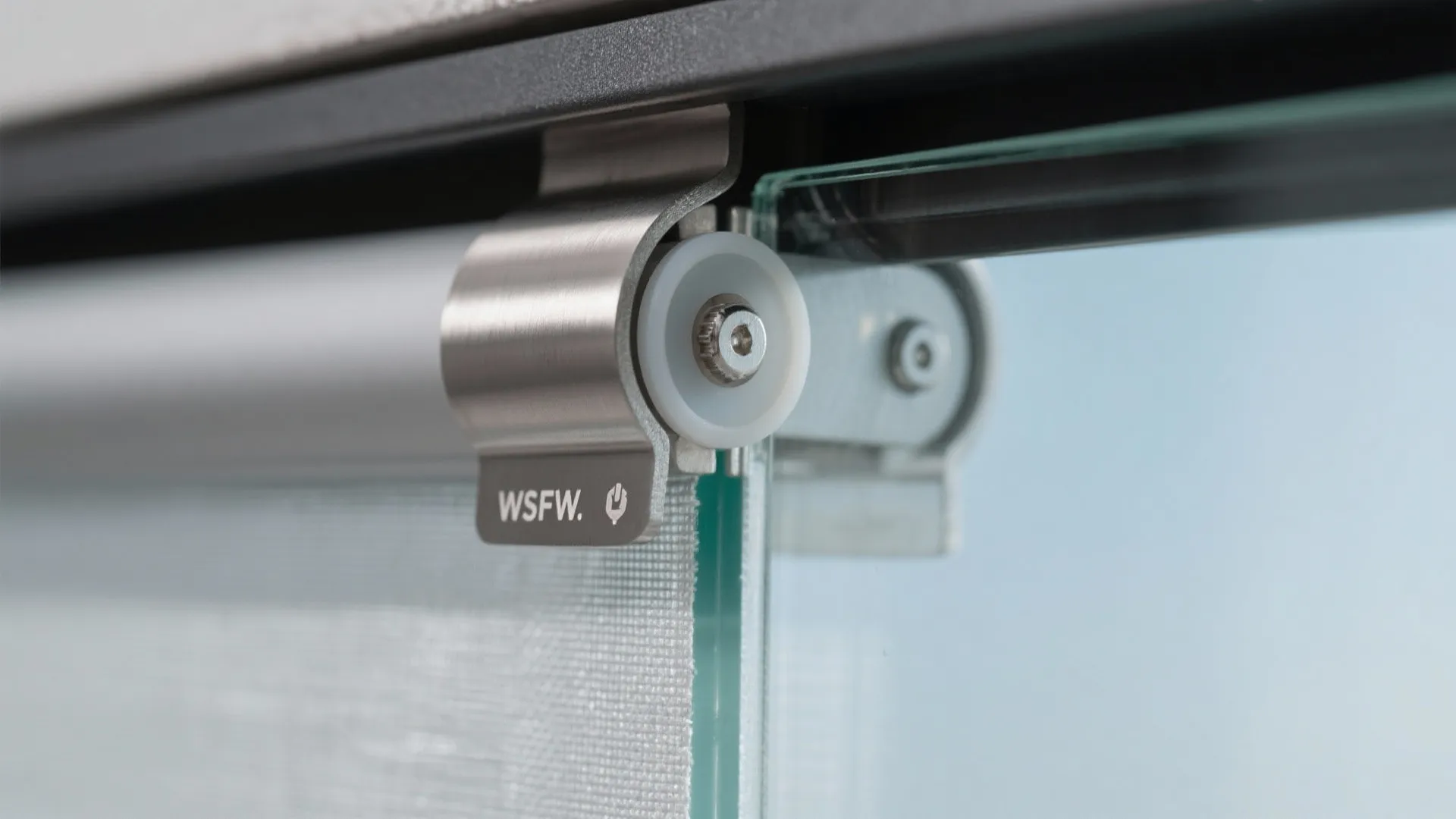 Close up of metal bracket and roller wheel holding a glass panel for sliding door