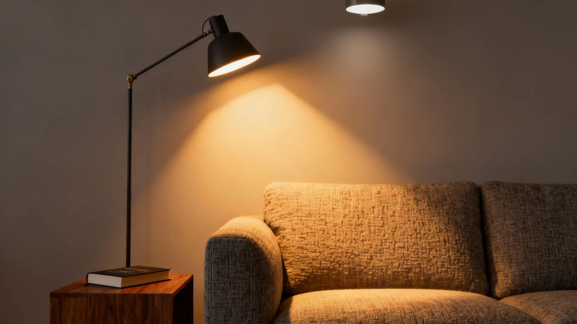Floor lamp beside a sofa angled for reading with warm light on lap area