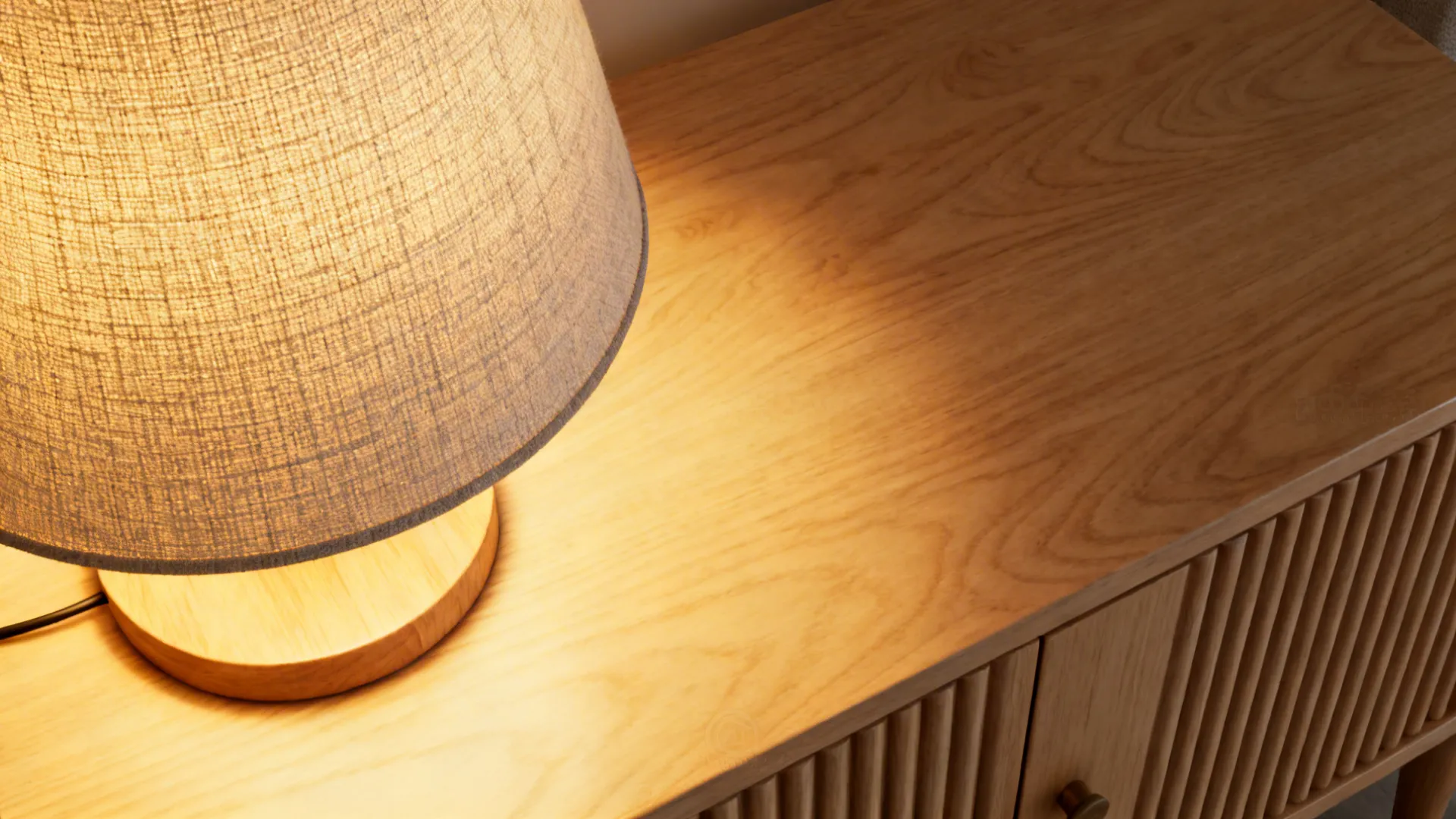 Macro of warm fabric-shaded lamp light on an oak nightstand and ribbed cabinet front.