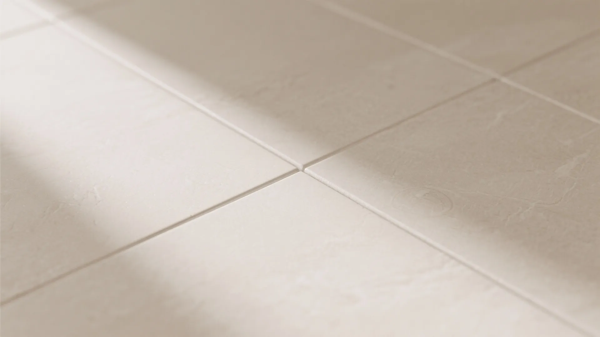 Close up view of light beige floor tiles with clean grout lines and natural soft sunlight