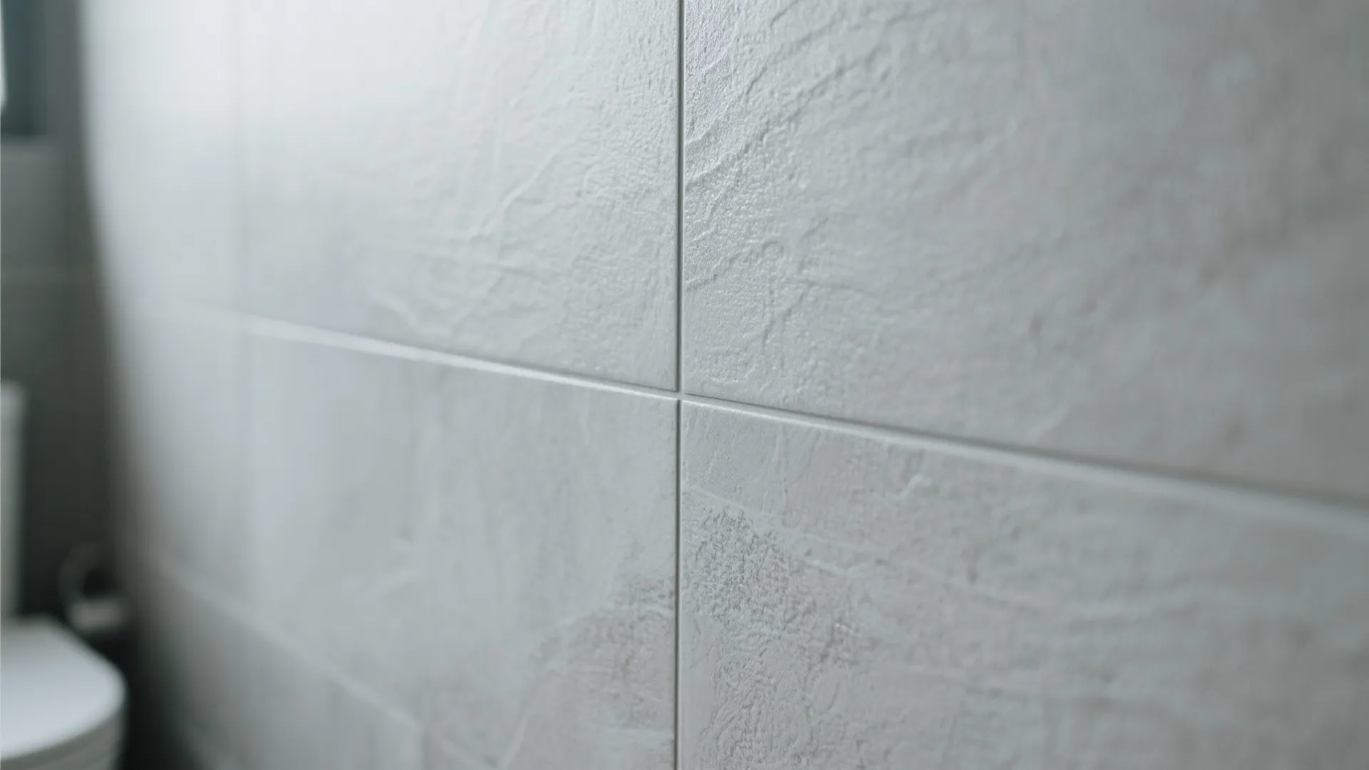 Close up view of grey textured wall tiles in a bathroom with clean thin grout