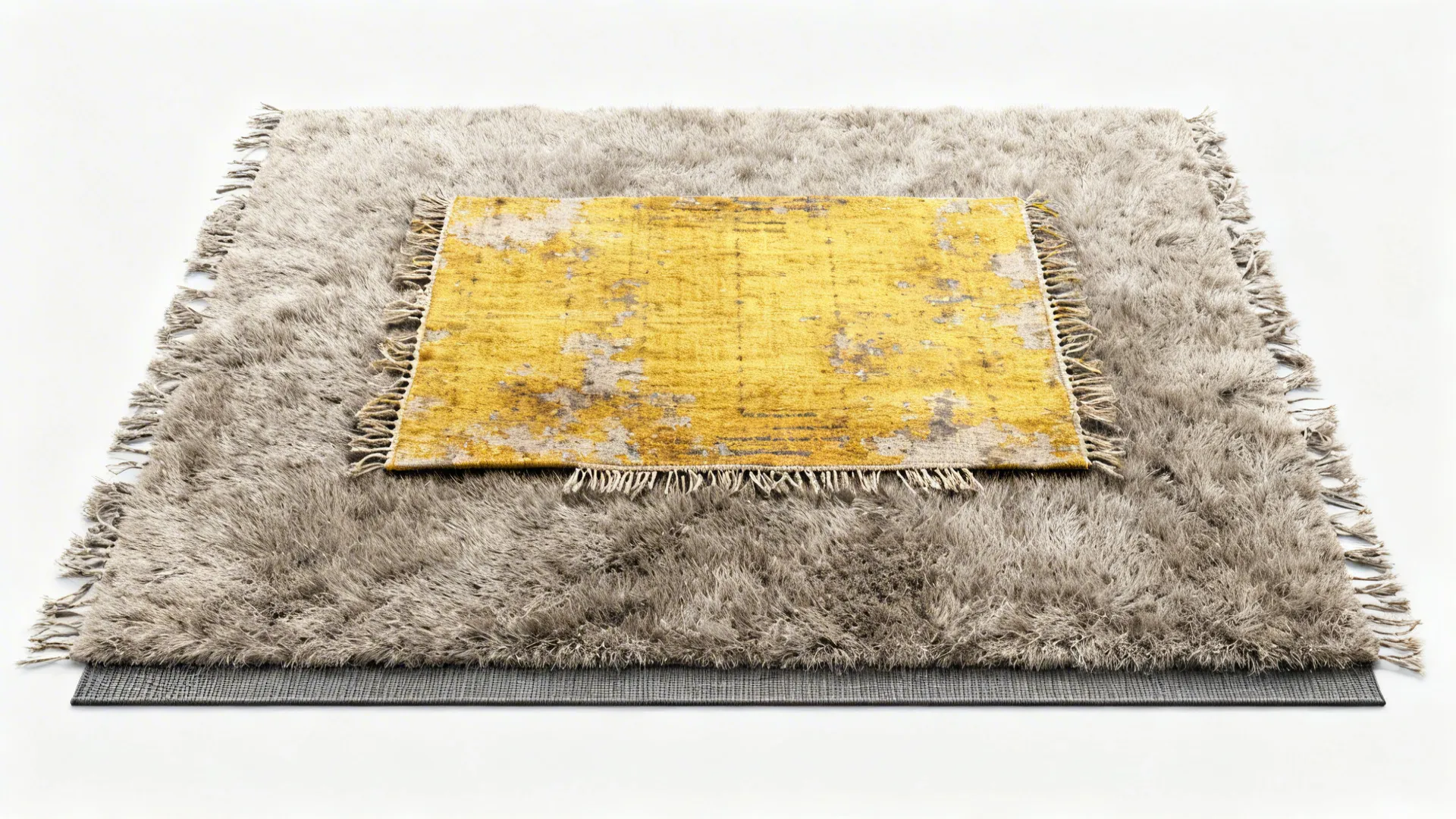 Top-down view of a mid-grey rug layered with a smaller distressed yellow kilim showing texture contrast