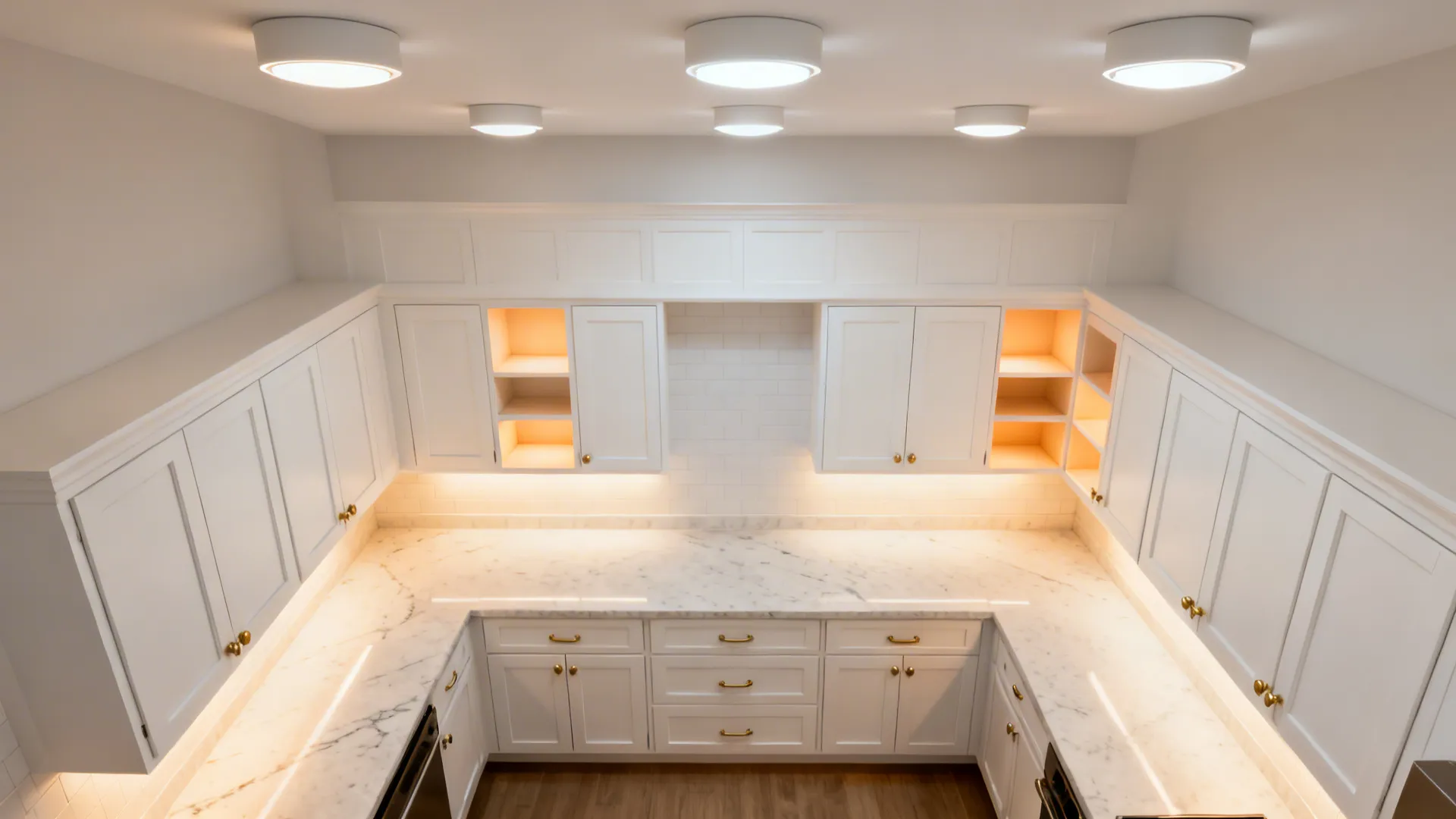 Top view of kitchen layout with white cabinets marble countertops under cabinet lights and ceiling lights