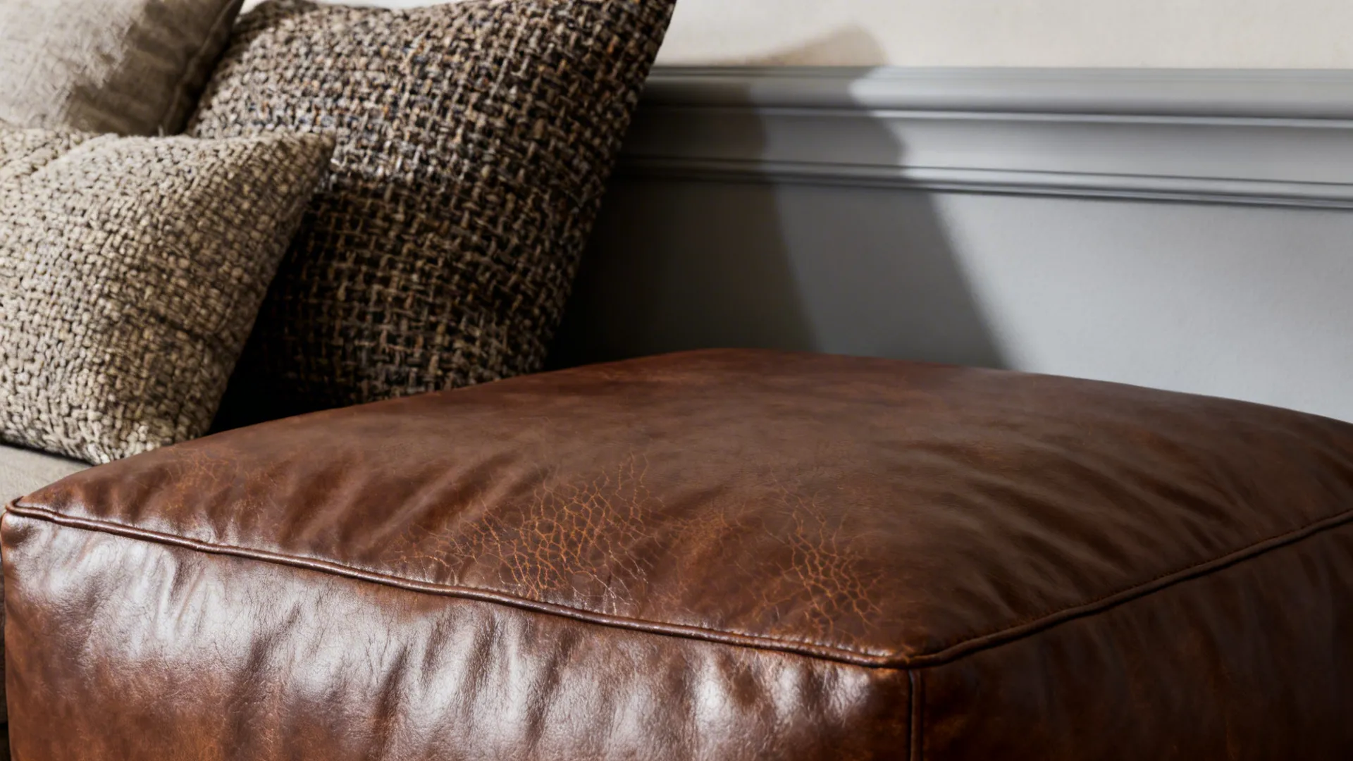 Close-up of chocolate ottoman, boucle cushions and light grey wall band