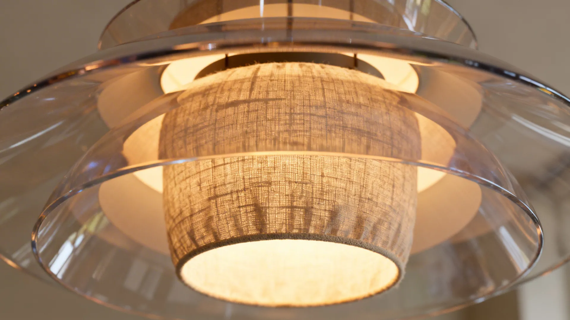 Close up of a modern ceiling light fixture with fabric inner shade and glass layers