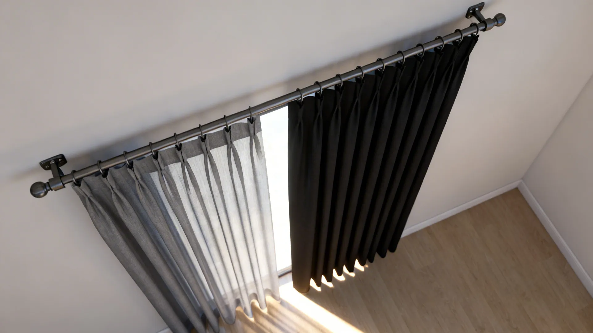 Top view of black and grey curtains hanging on a metal rod over wood flooring