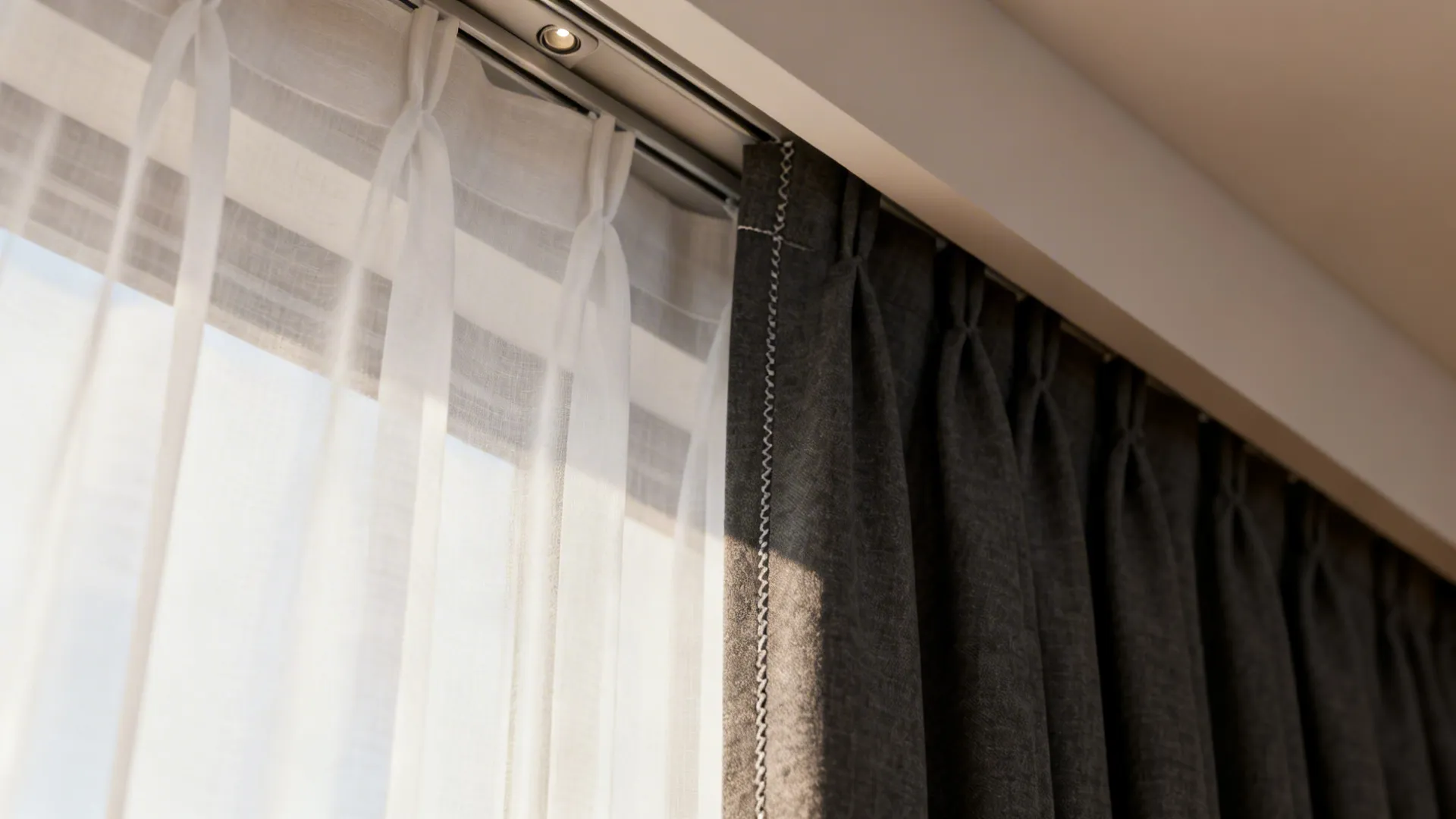 Close-up of layered sheer and blackout curtains showing fabric texture and track