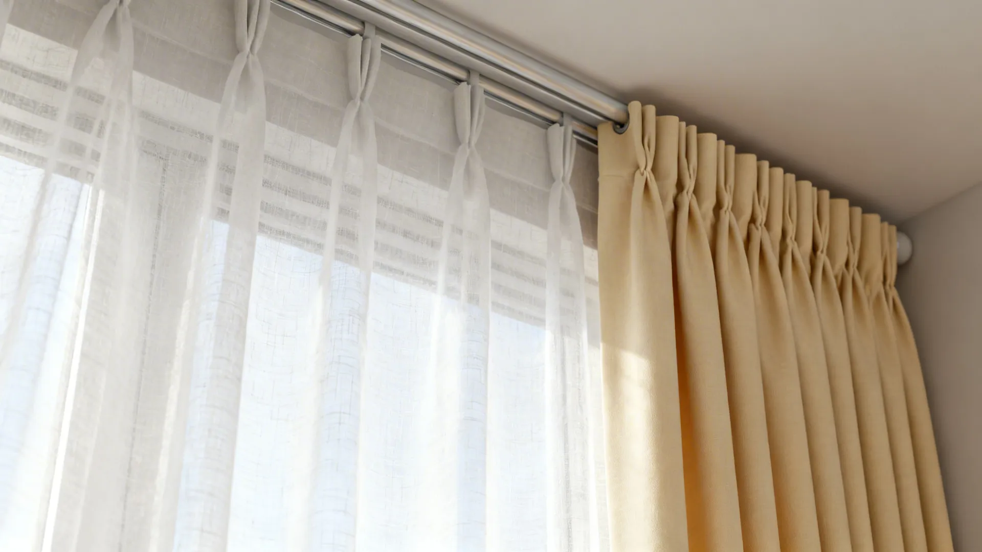 Close-up of layered sheer and cream blackout panel on a double rod with soft daylight