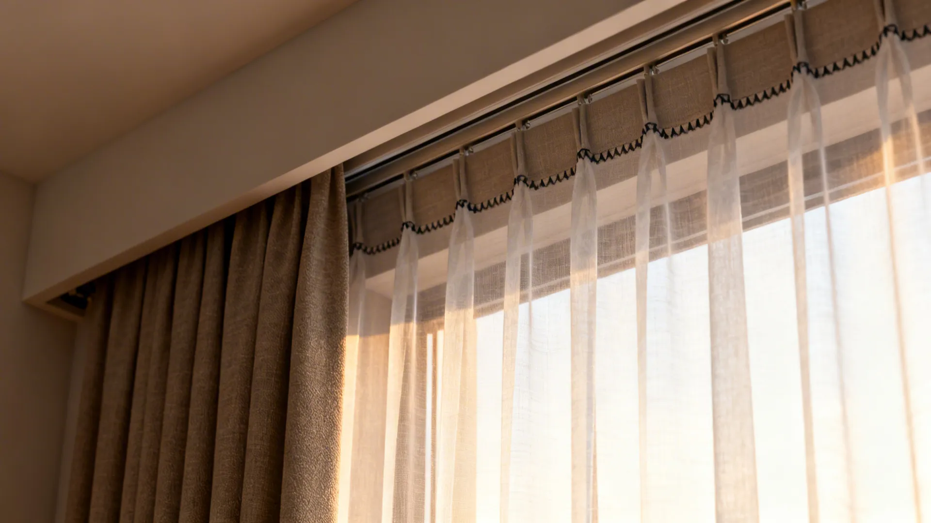 Close up of beige curtains and white sheer curtains with black stitching details near a window