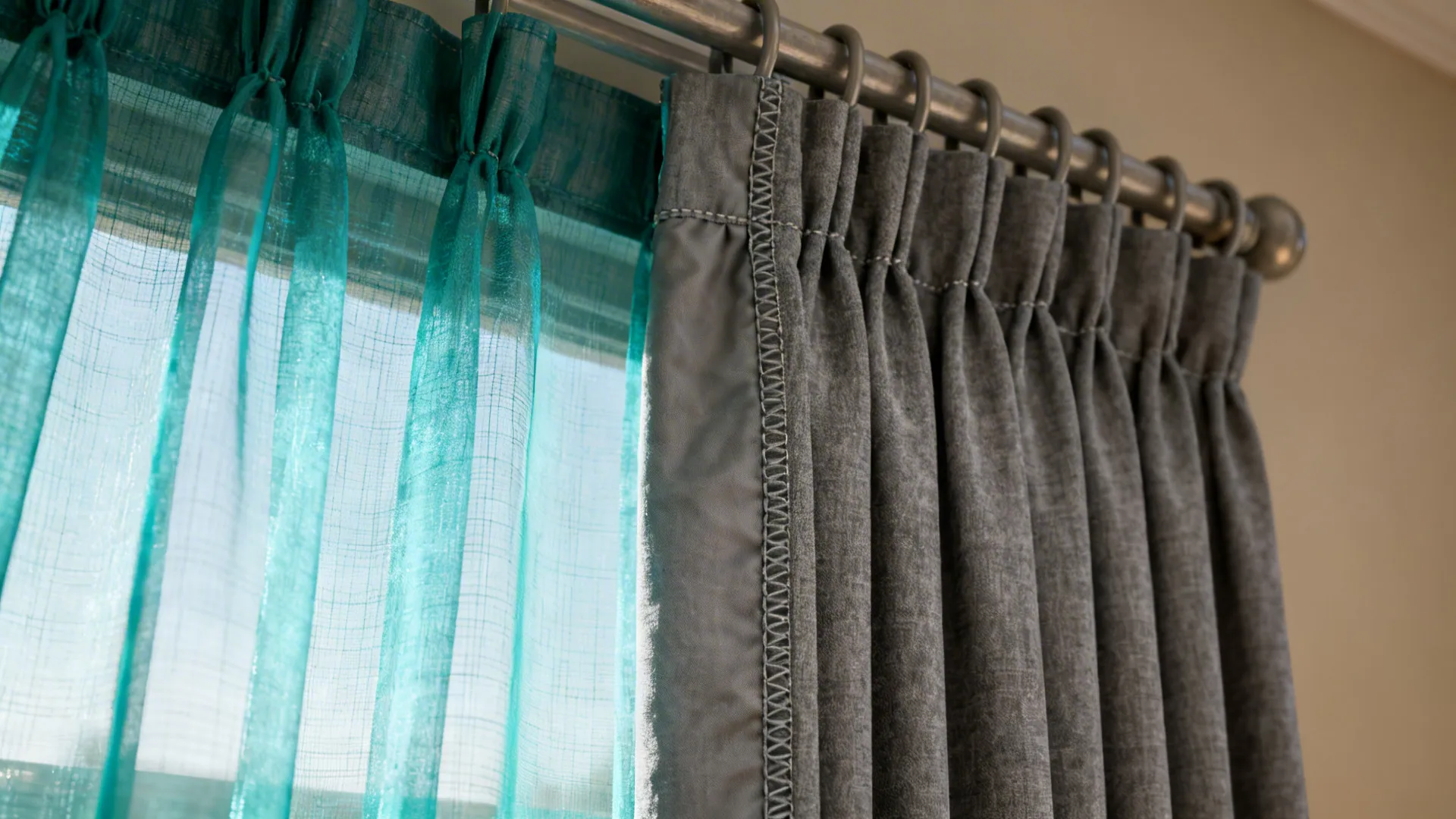 Close-up of teal sheer layered over gray blackout curtain showing texture and stitching.