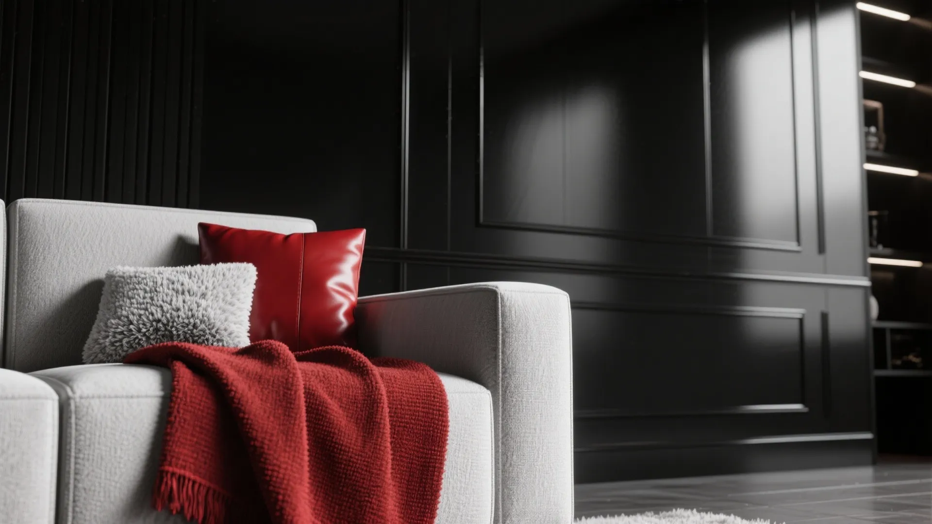 Grey sofa with red pillows and red blanket against a black wall panel in living room