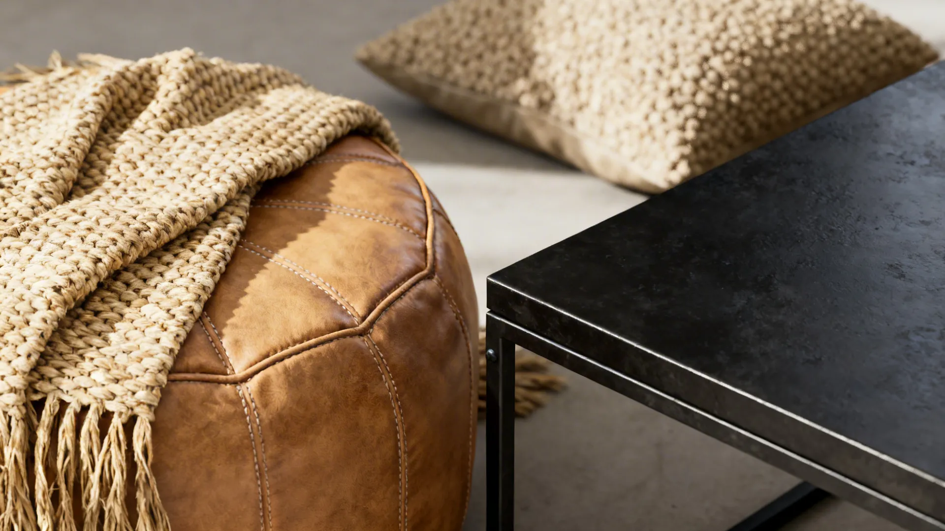 Close-up of matte black metal, tan leather, and woven natural fibers layered together.