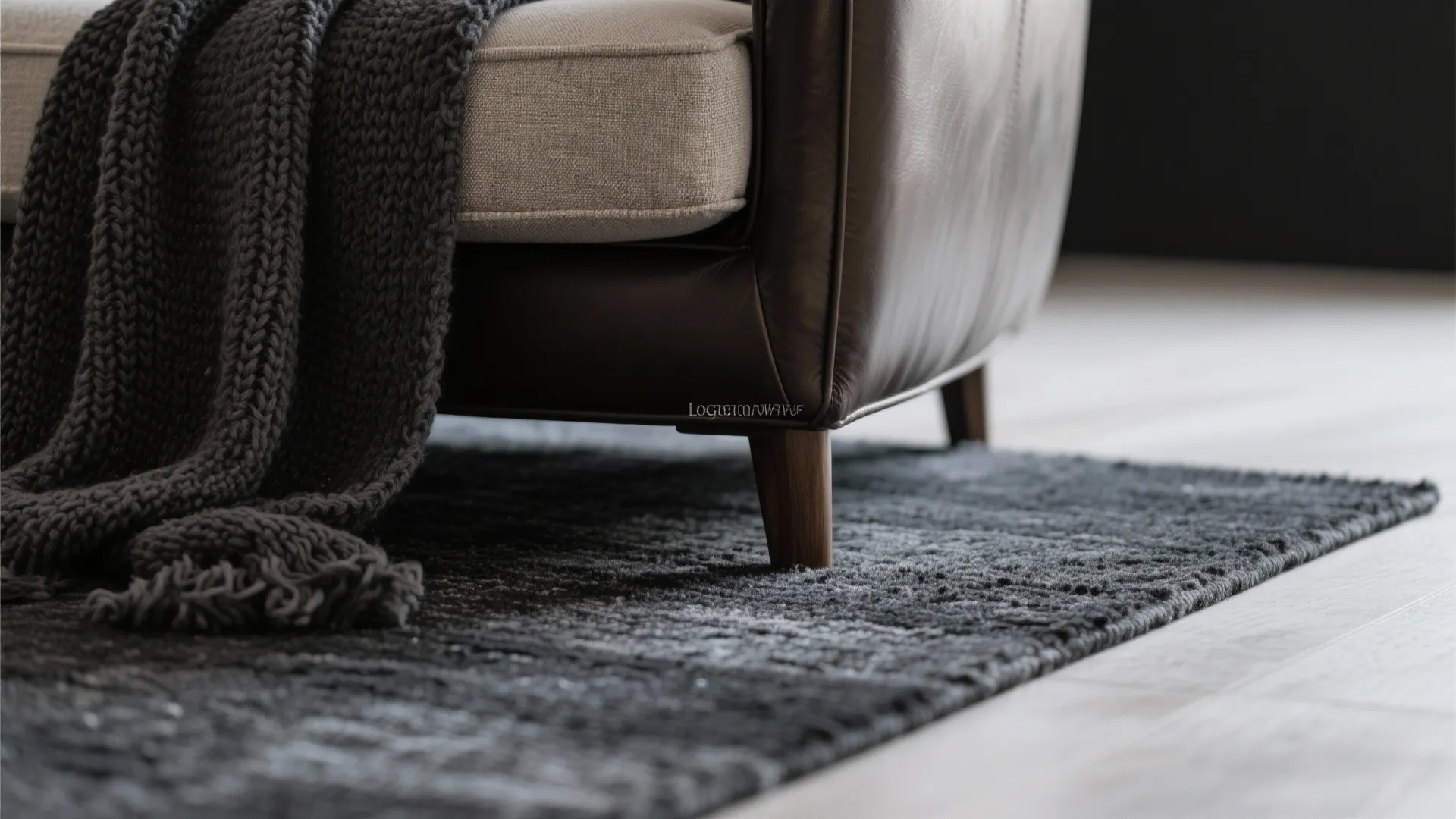 Close up of leather chair with grey knitted blanket on a dark textured area carpet