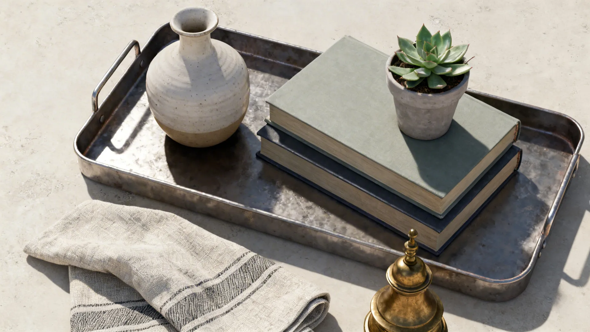 Top-down tray on a coffee table with stacked books, ceramic vase, succulent and brass object