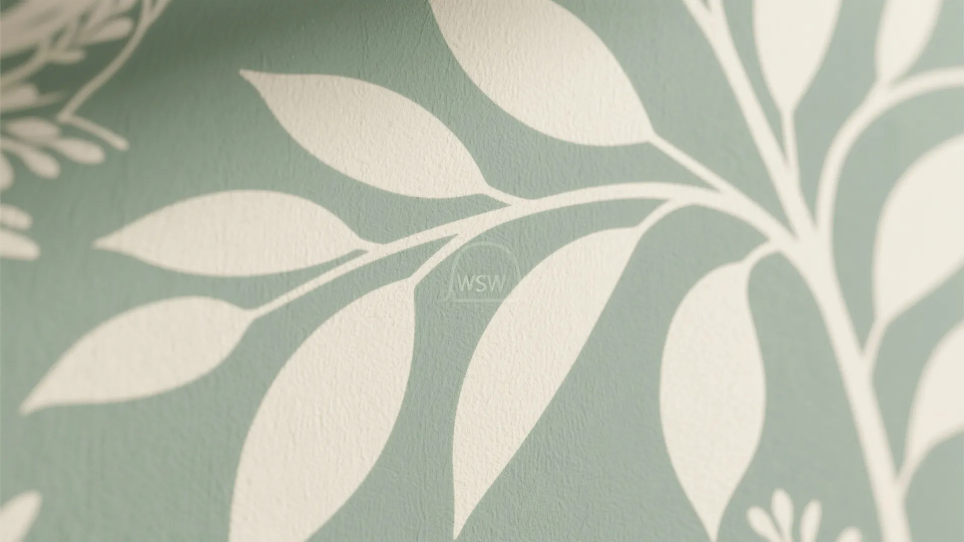 Close up view of a light green wallpaper with white leaf patterns in soft lighting