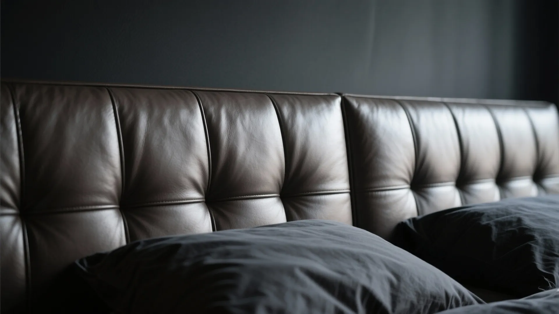 Close up of brown leather headboard with tufted design and grey pillows in modern bedroom