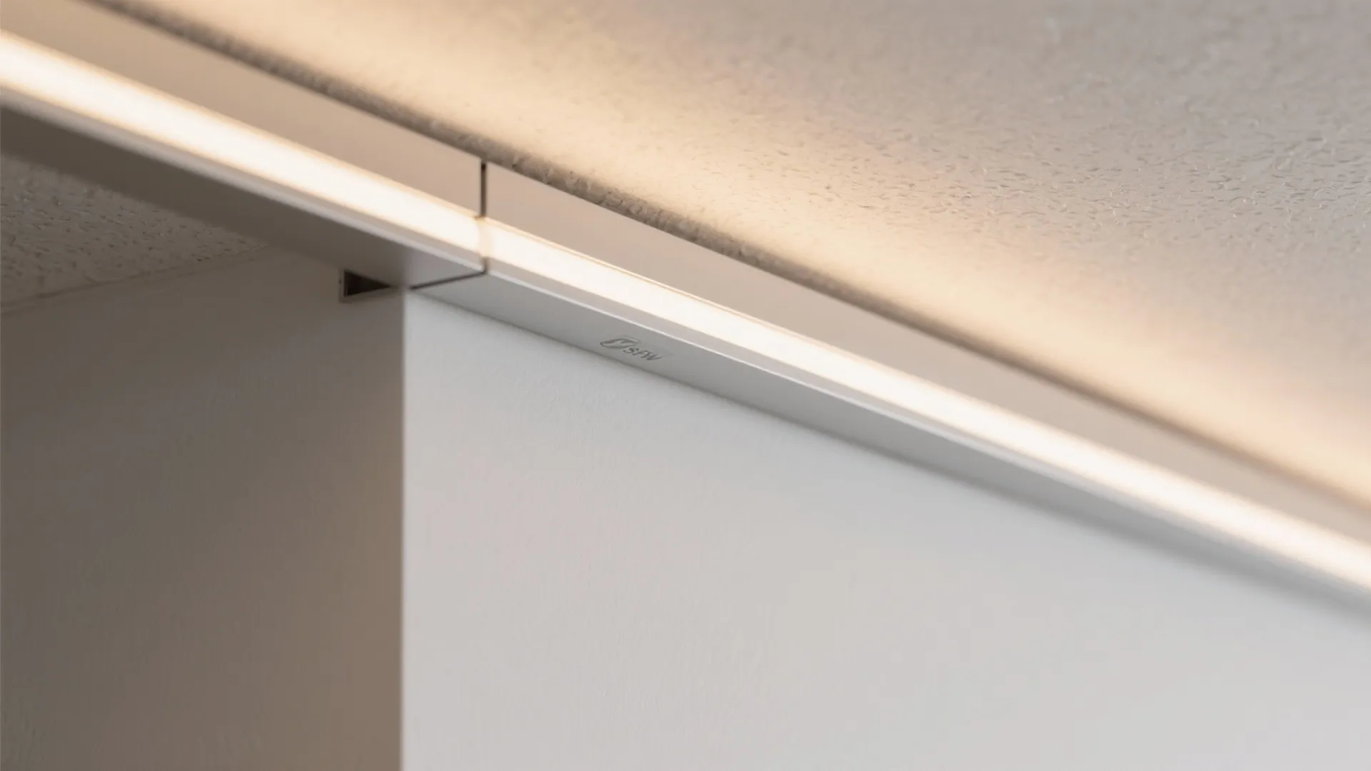 Close up view of a slim light fixture installed on a white wall and ceiling