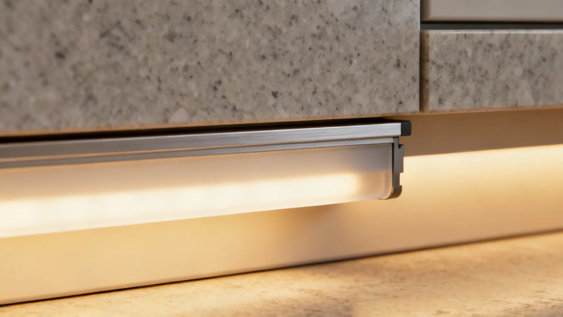 Warm light strip installed under a grey stone kitchen counter providing soft and functional light