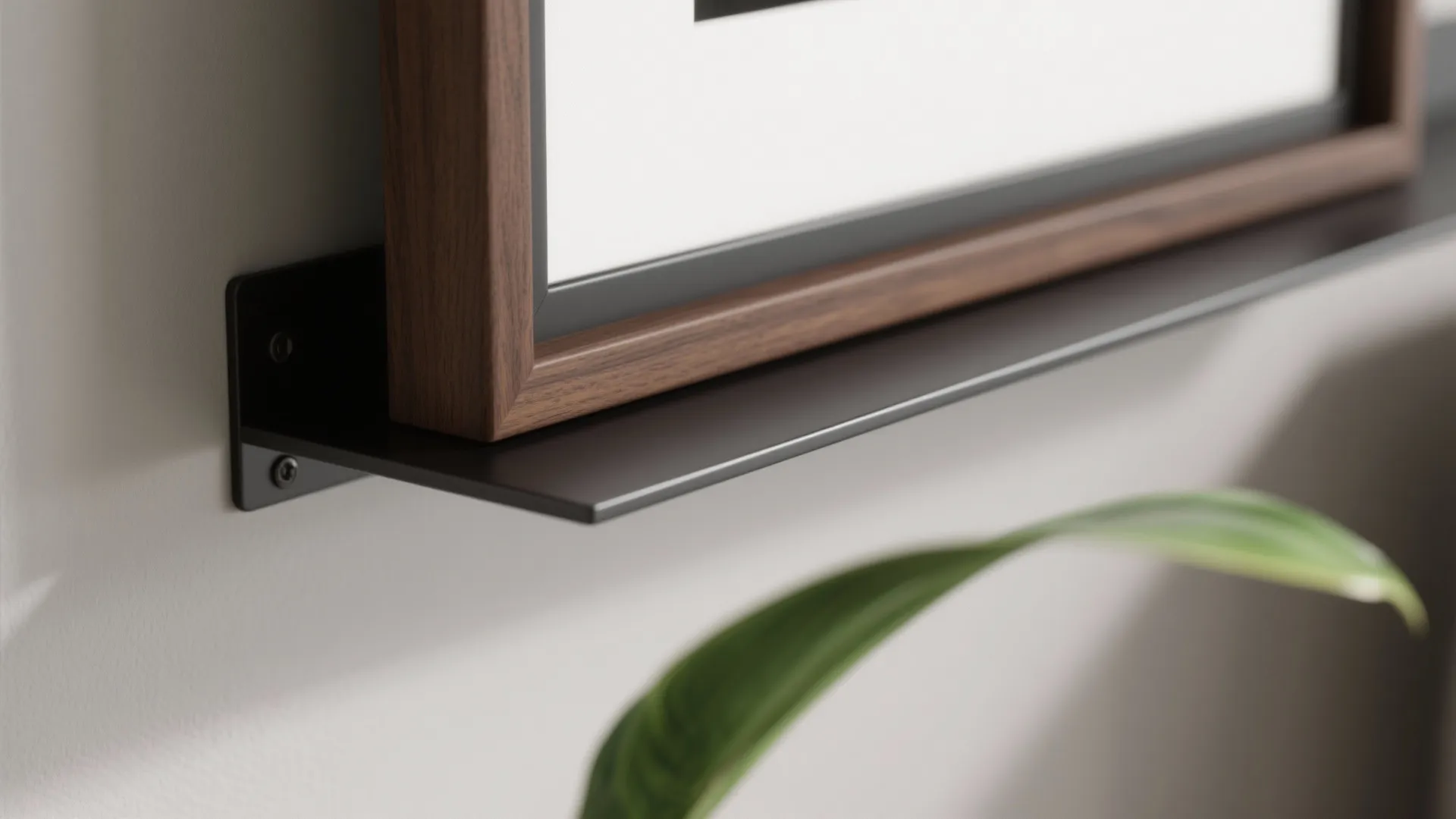 Close up of a black metal shelf bracket holding a wooden picture frame against wall