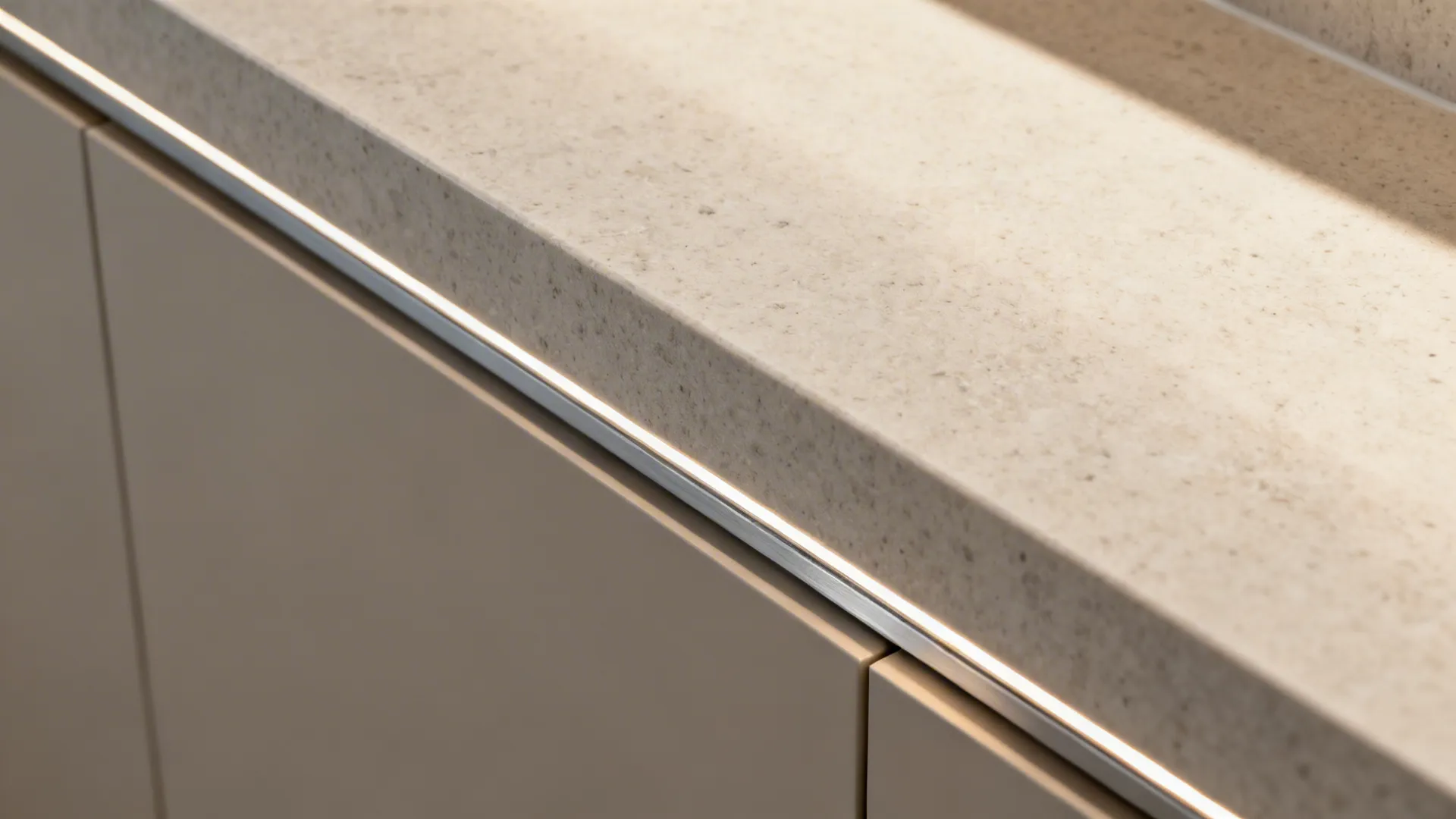Macro view of a countertop-to-backsplash ledge joint with silicone and concealed LED channel.