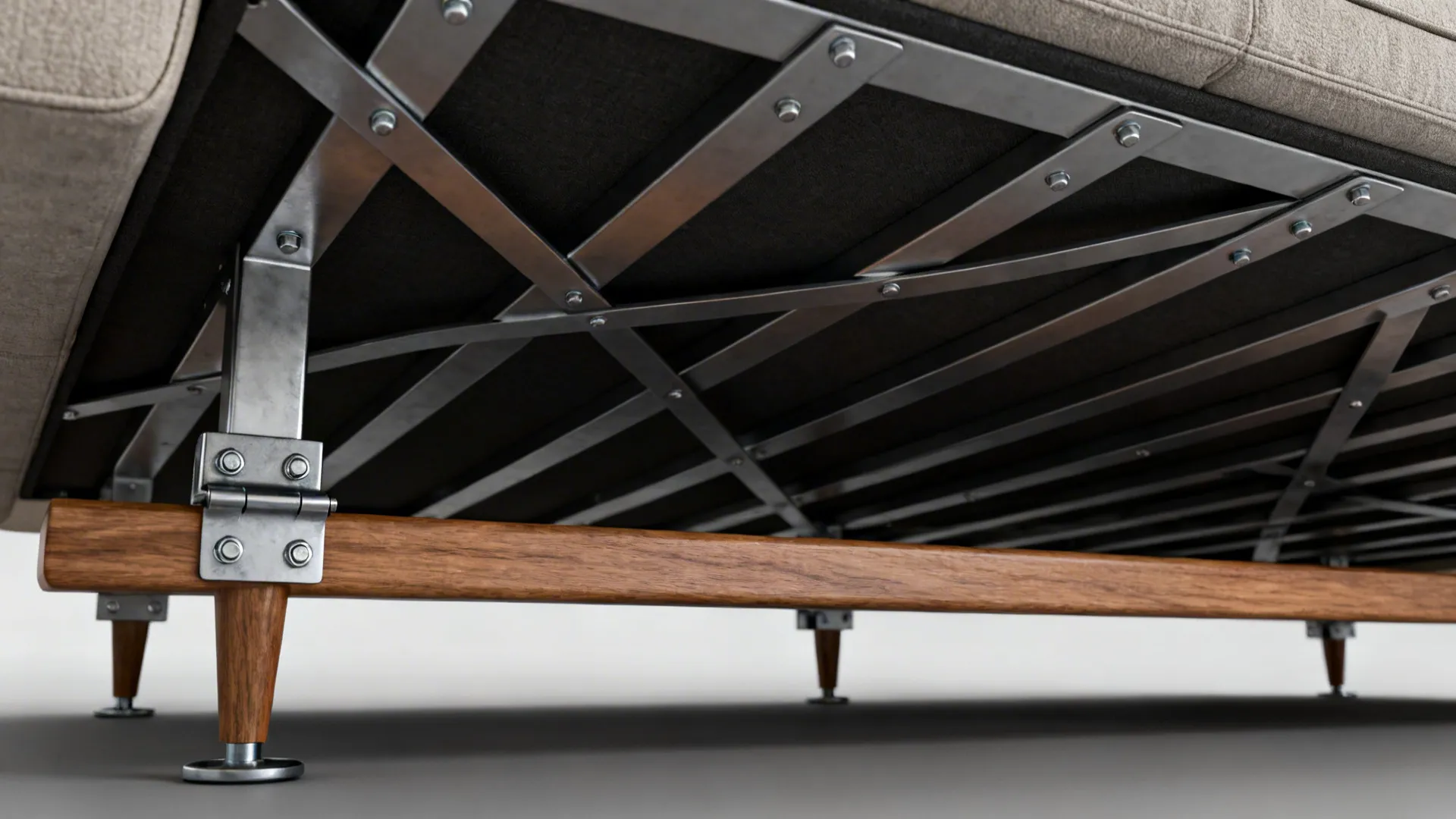 Underside of a sofa showing steel cross-bracing, metal leg plates, and full-length stretcher for reinforcement.