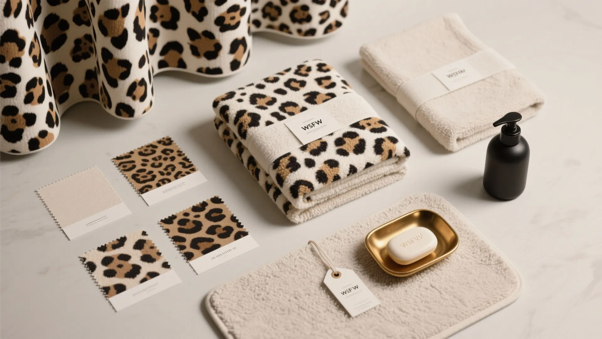 Leopard print towels and fabric samples displayed on a white table with soap and bottle