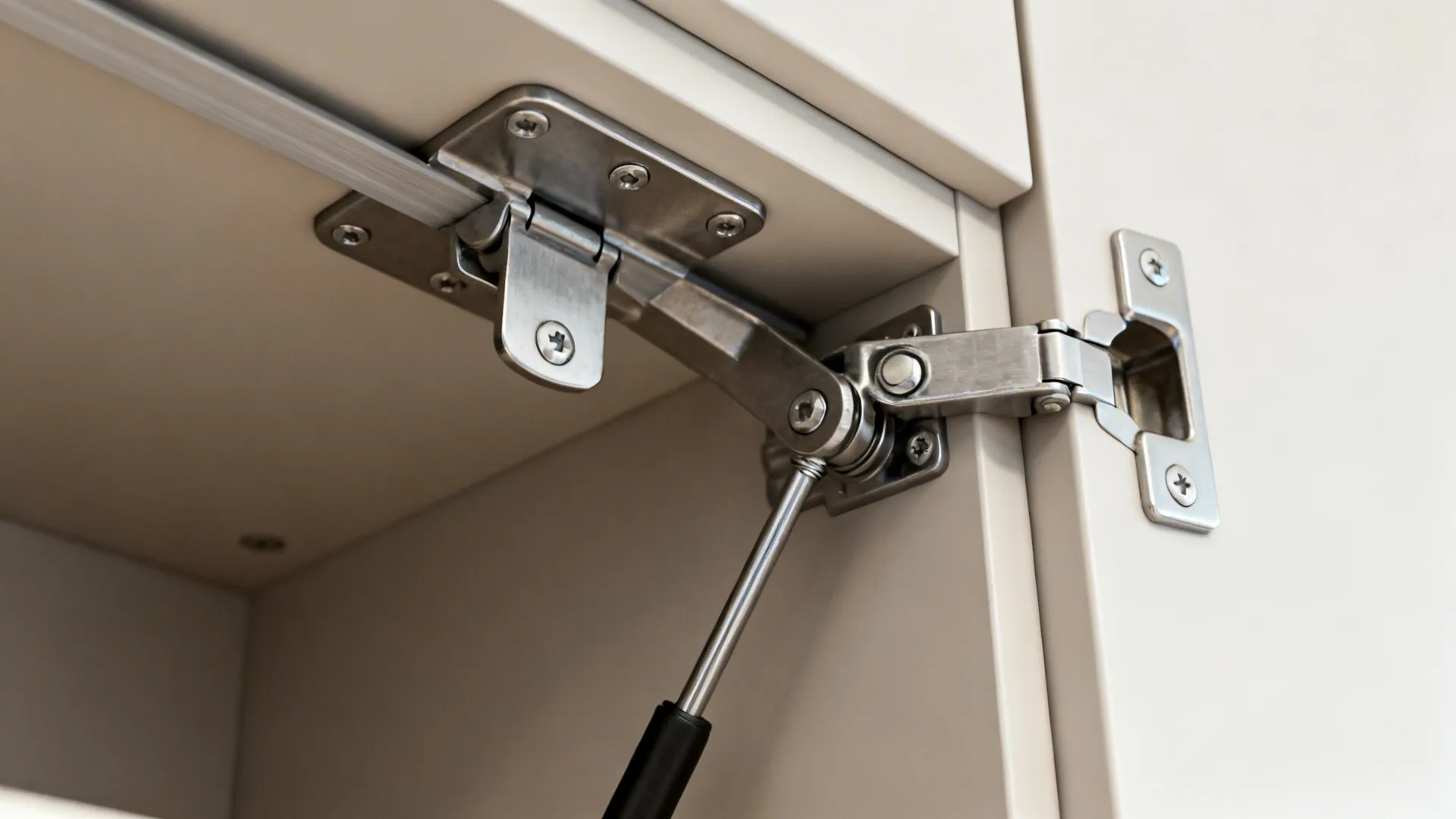 Macro of a lift-up hinge and gas strut on an overhead cabinet door.