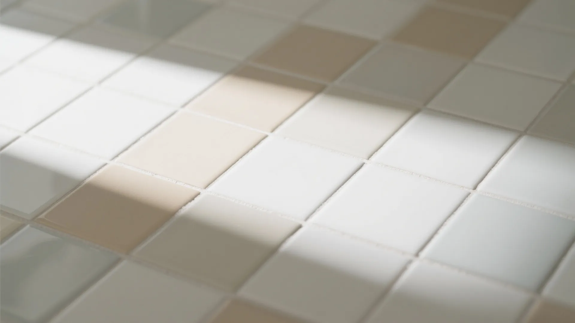 Close up of square cream and white bathroom floor tiles with soft sunlight and shadows
