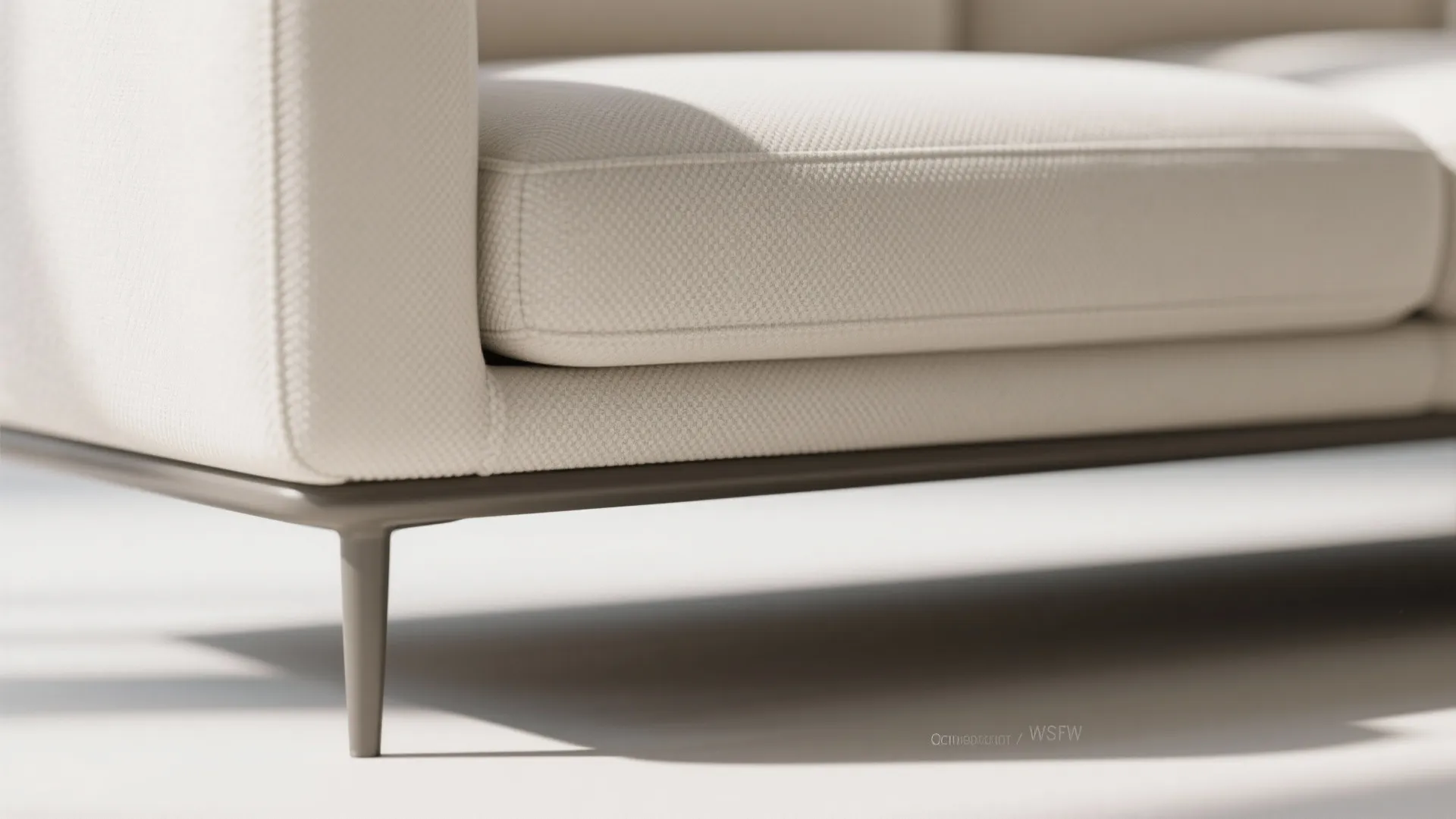 Close up view of a beige sofa cushion with thin grey metal legs on white background