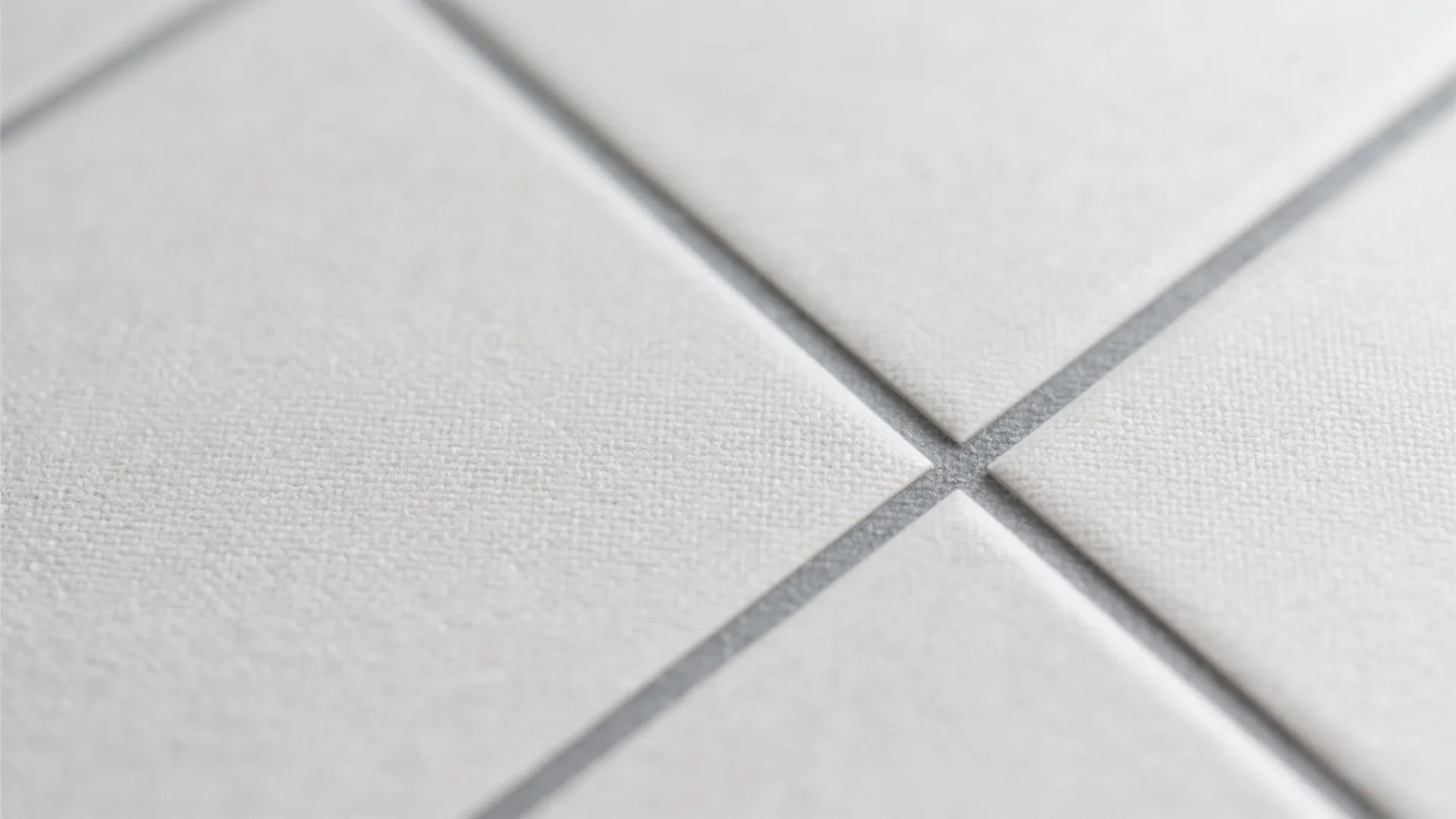 Close up of white square floor tiles with grey grout lines and a clean finish