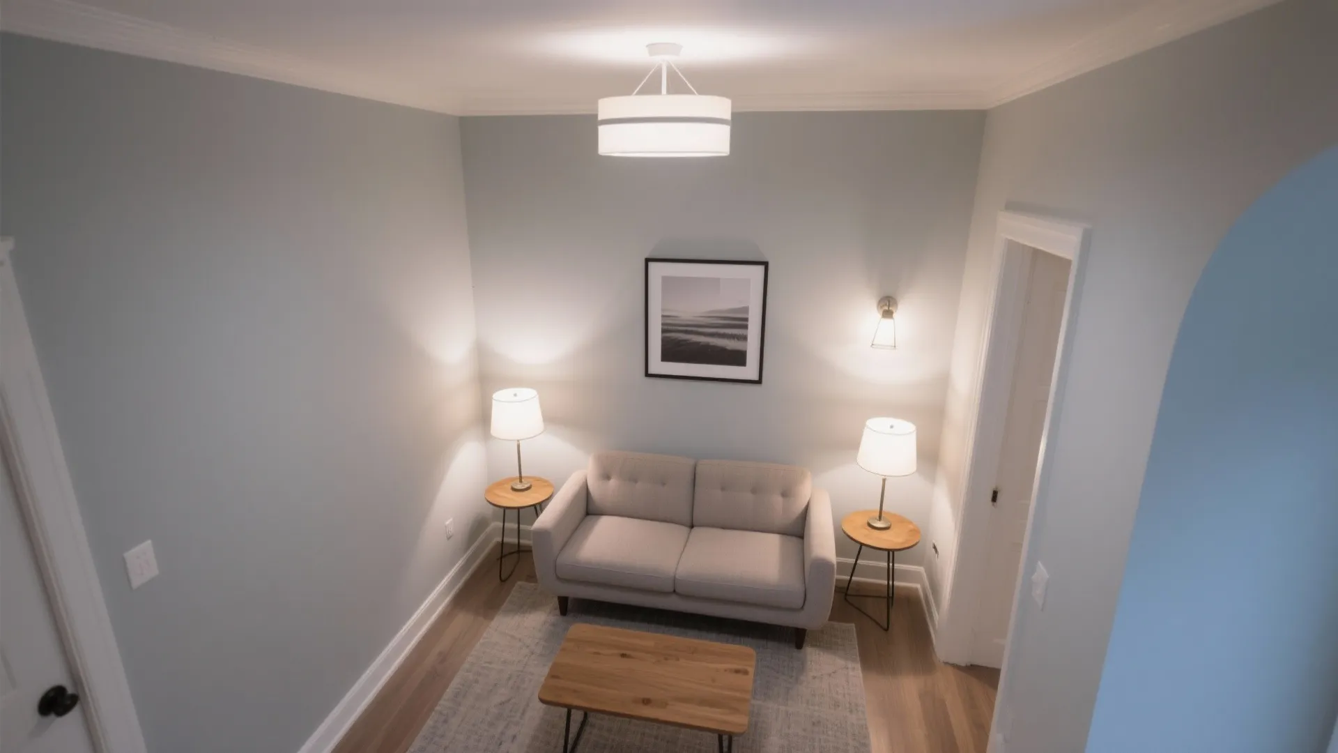 Top view of a small living room with light gray walls sofa and ceiling light
