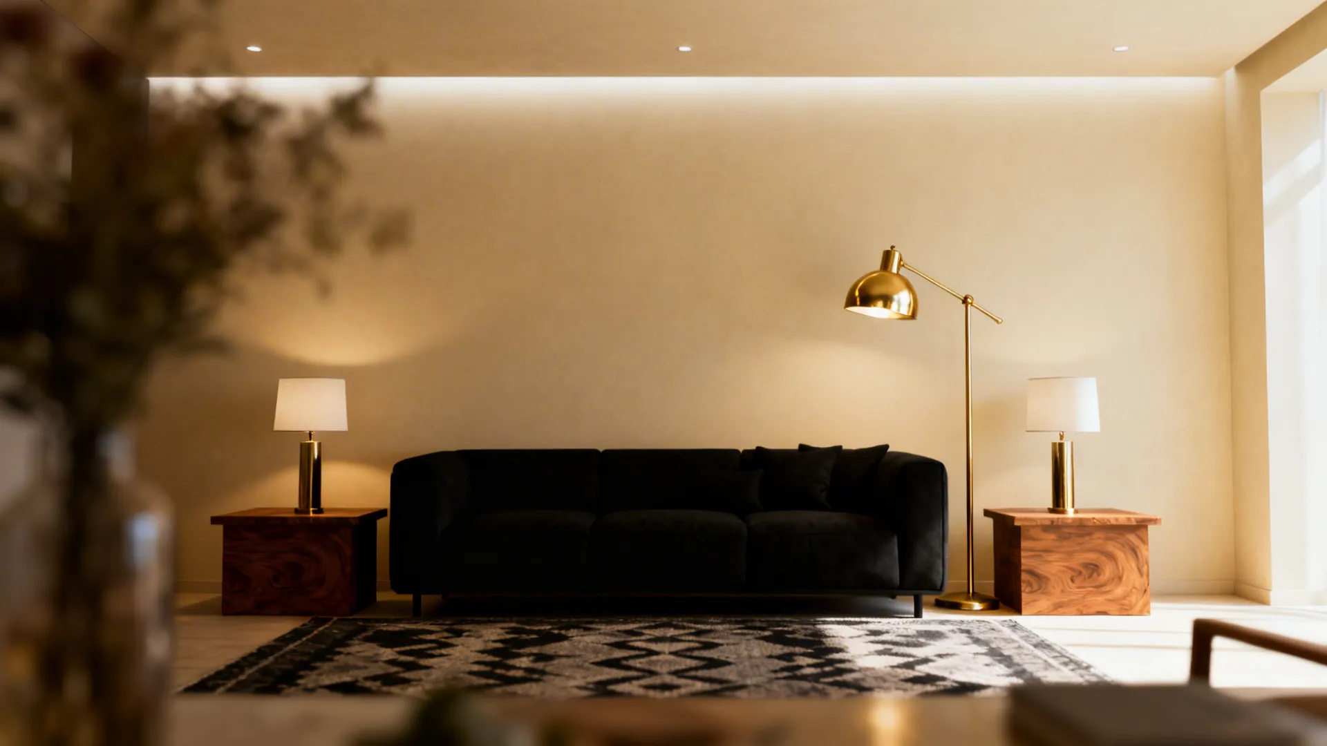 Black sofa on light cream walls with layered ceiling, floor and table lighting creating contrast and mood.
