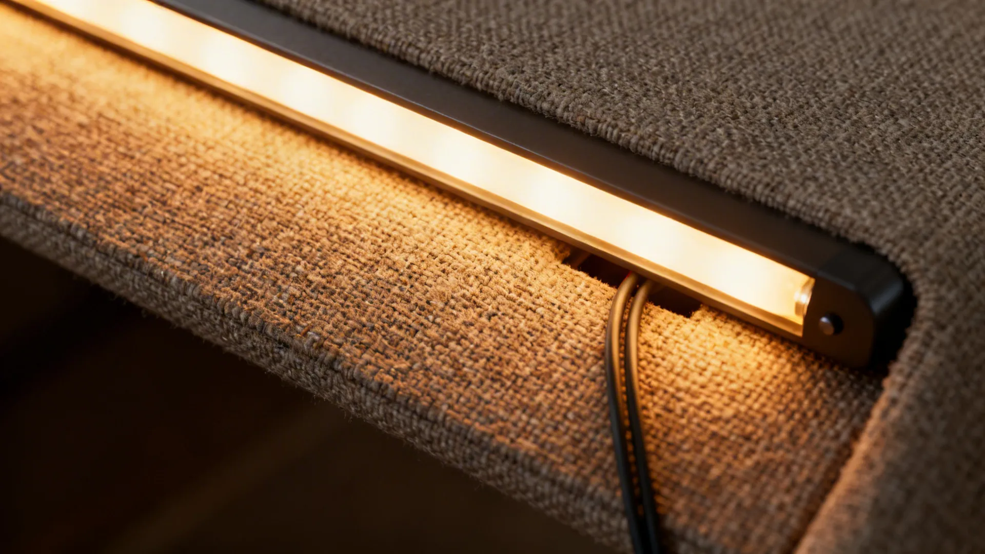 Close up of warm light fixture strip installed on brown fabric surface in a modern bedroom