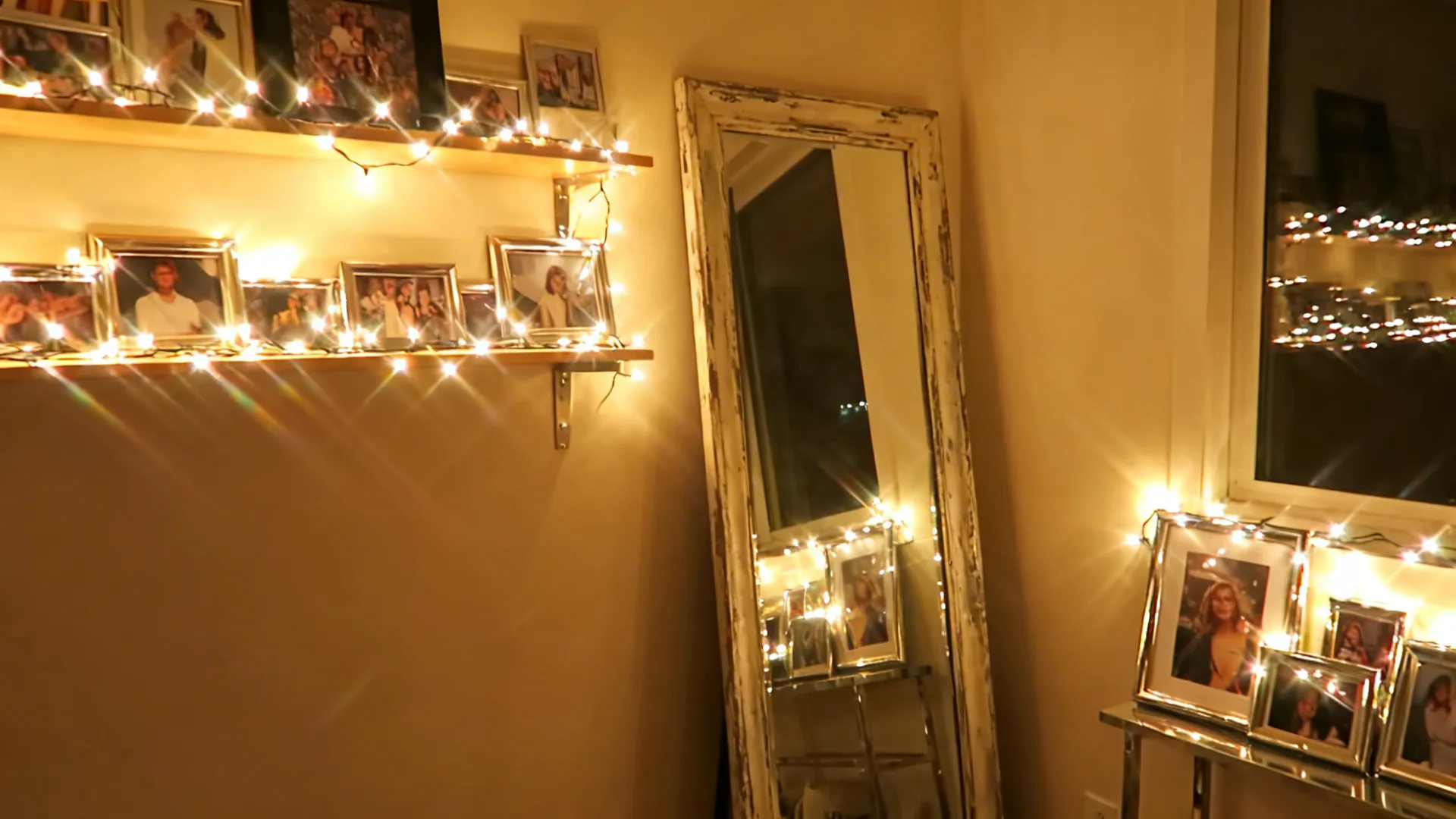 Fairy lights layered over a mirror and framed photos, multiplying warm glow