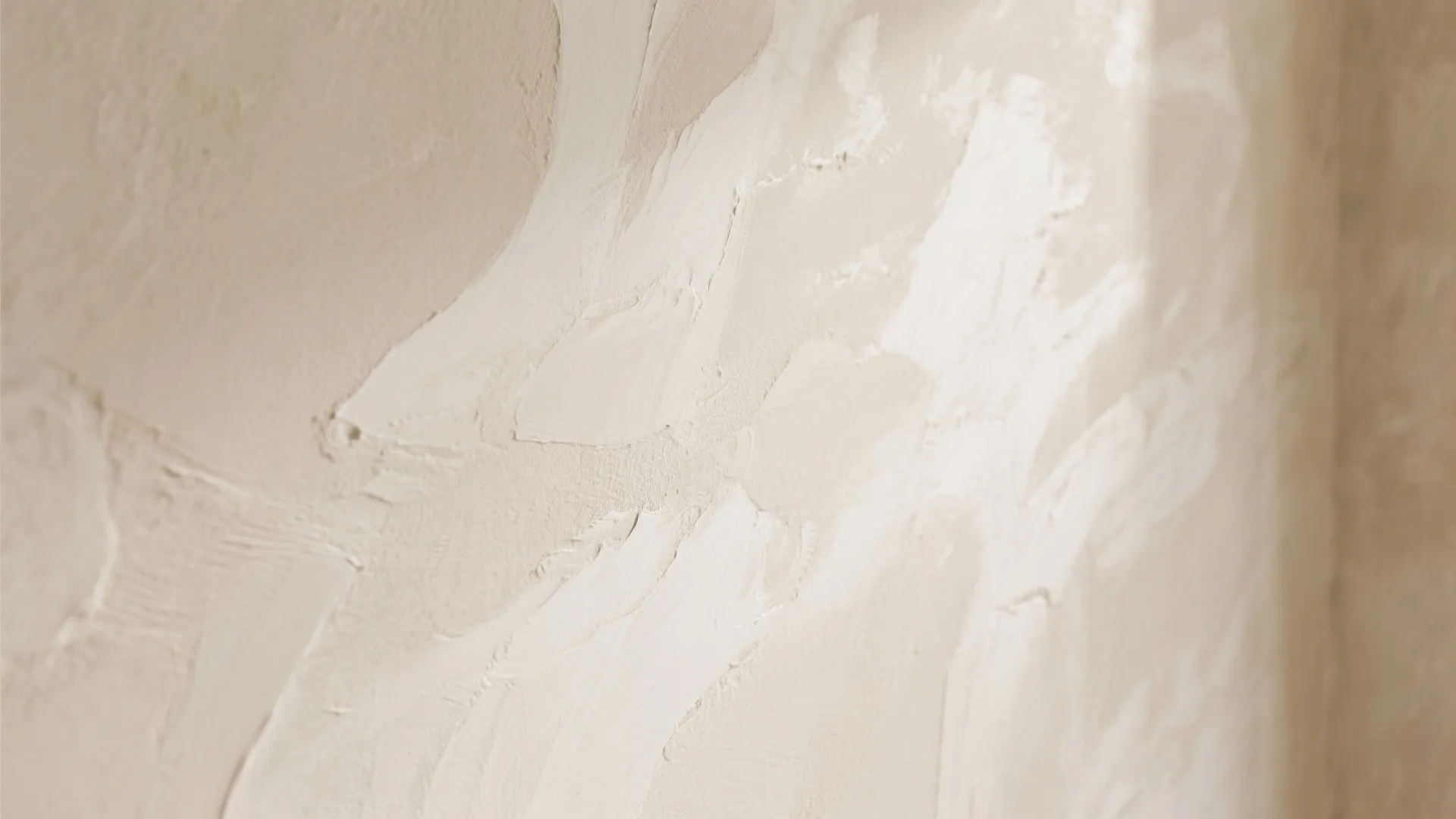 Close up view of textured beige wall paint with visible brush strokes and soft lighting