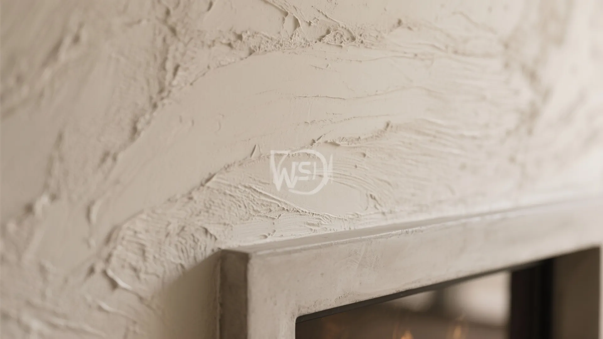 Close up of textured beige wall with rough plaster strokes above a simple stone frame