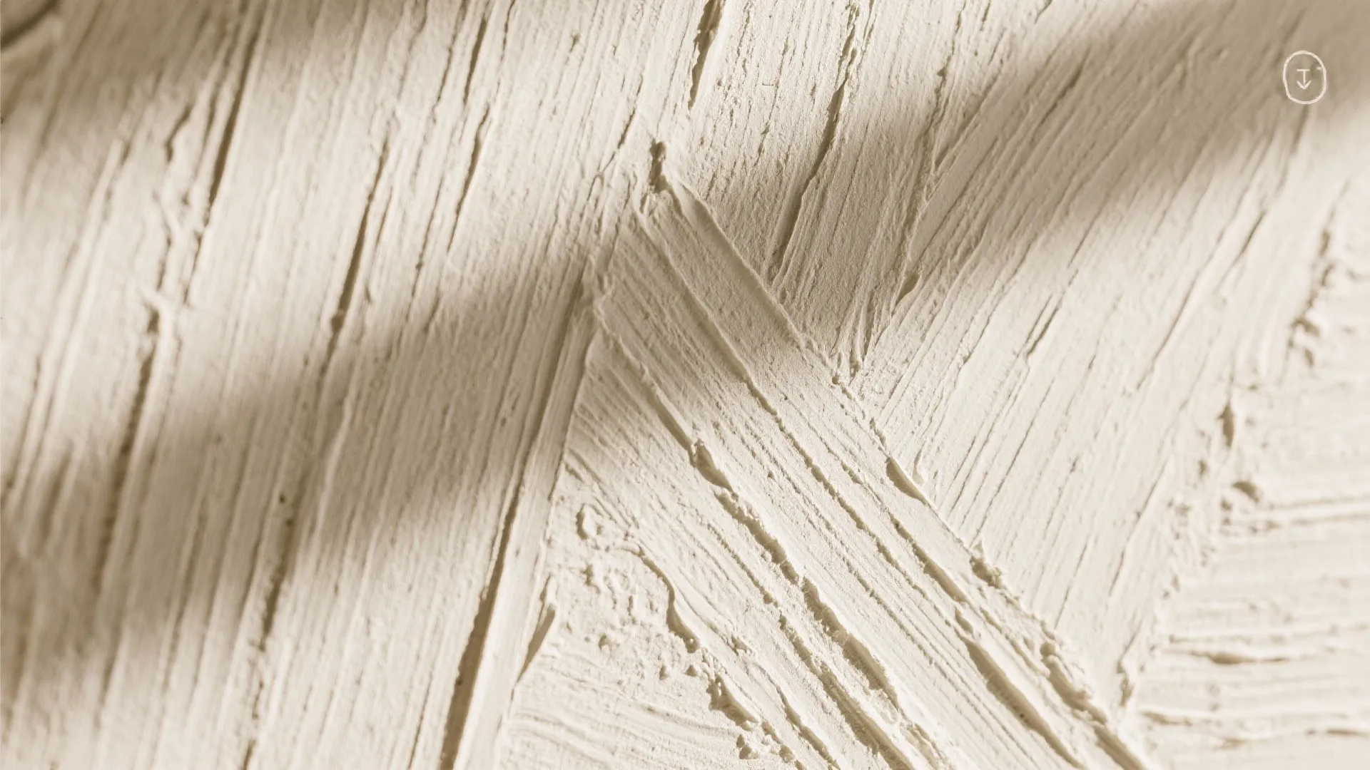 Close-up of a textured beige wall with visible brush strokes and soft natural sunlight shadows