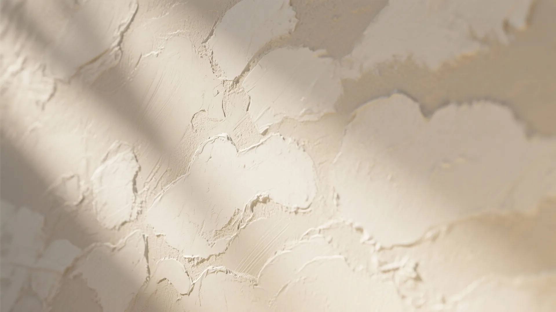 Close up view of textured beige wall plaster finish with soft diagonal shadows and natural