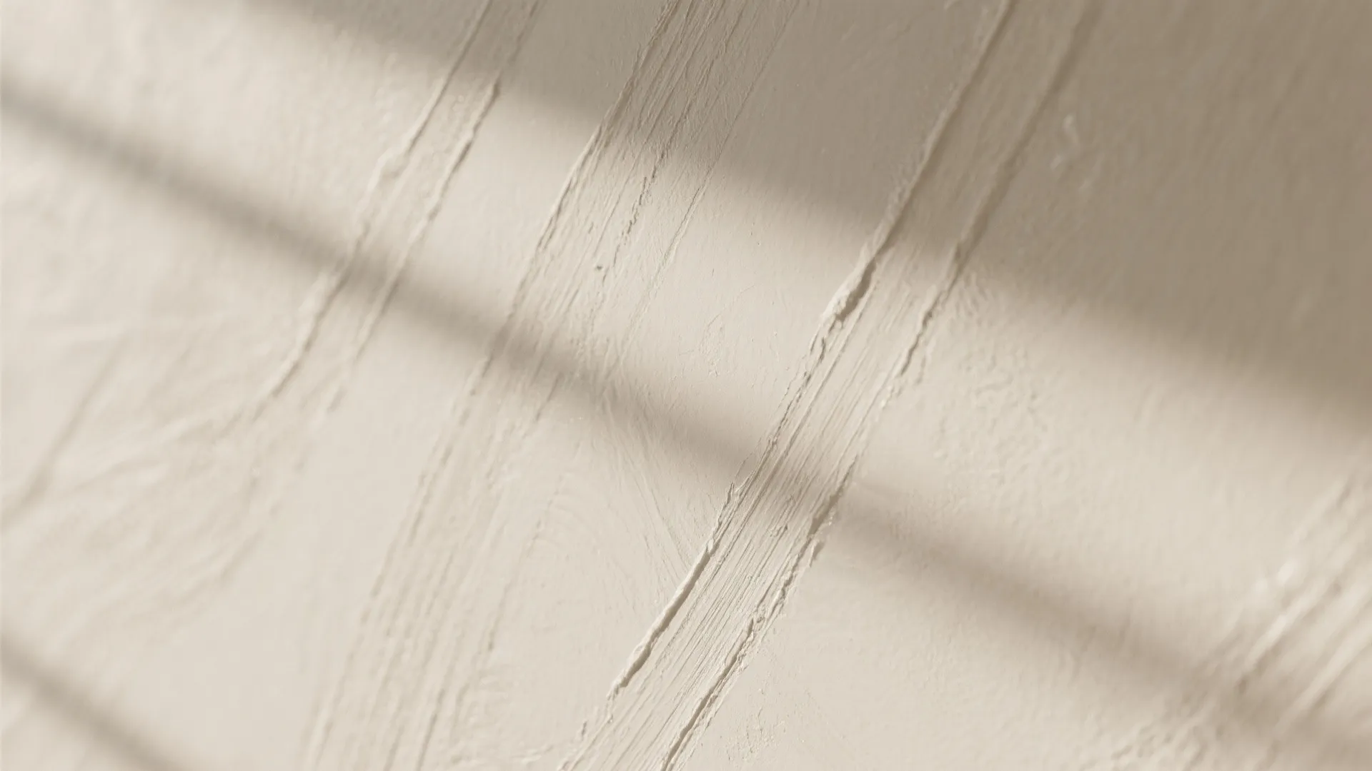 Close up view of textured beige wall surface with soft shadows from nearby window light